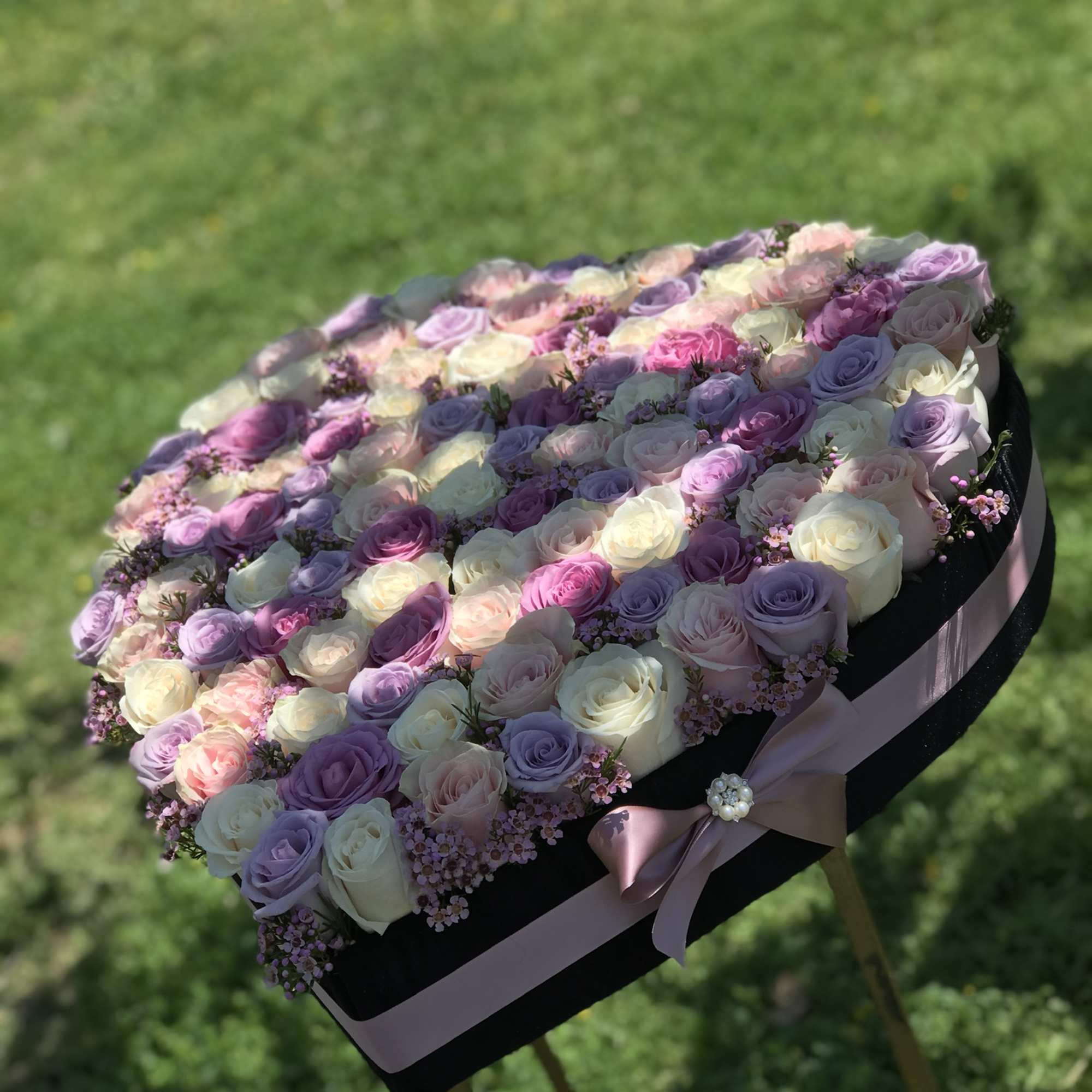 Heart-shaped arrangement of pastel roses with a pink ribbon