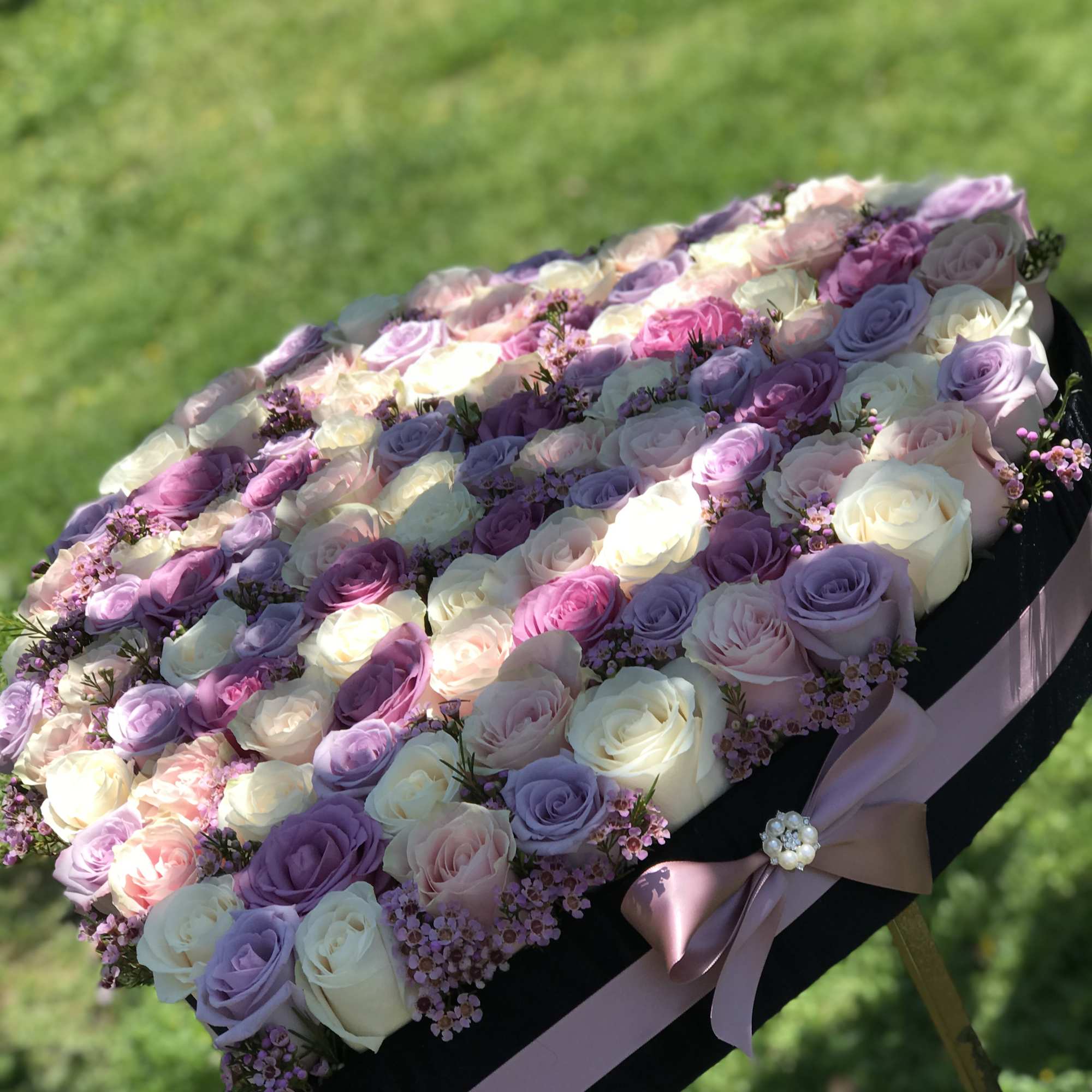 Large pastel rose arrangement in a black box with a pink ribbon