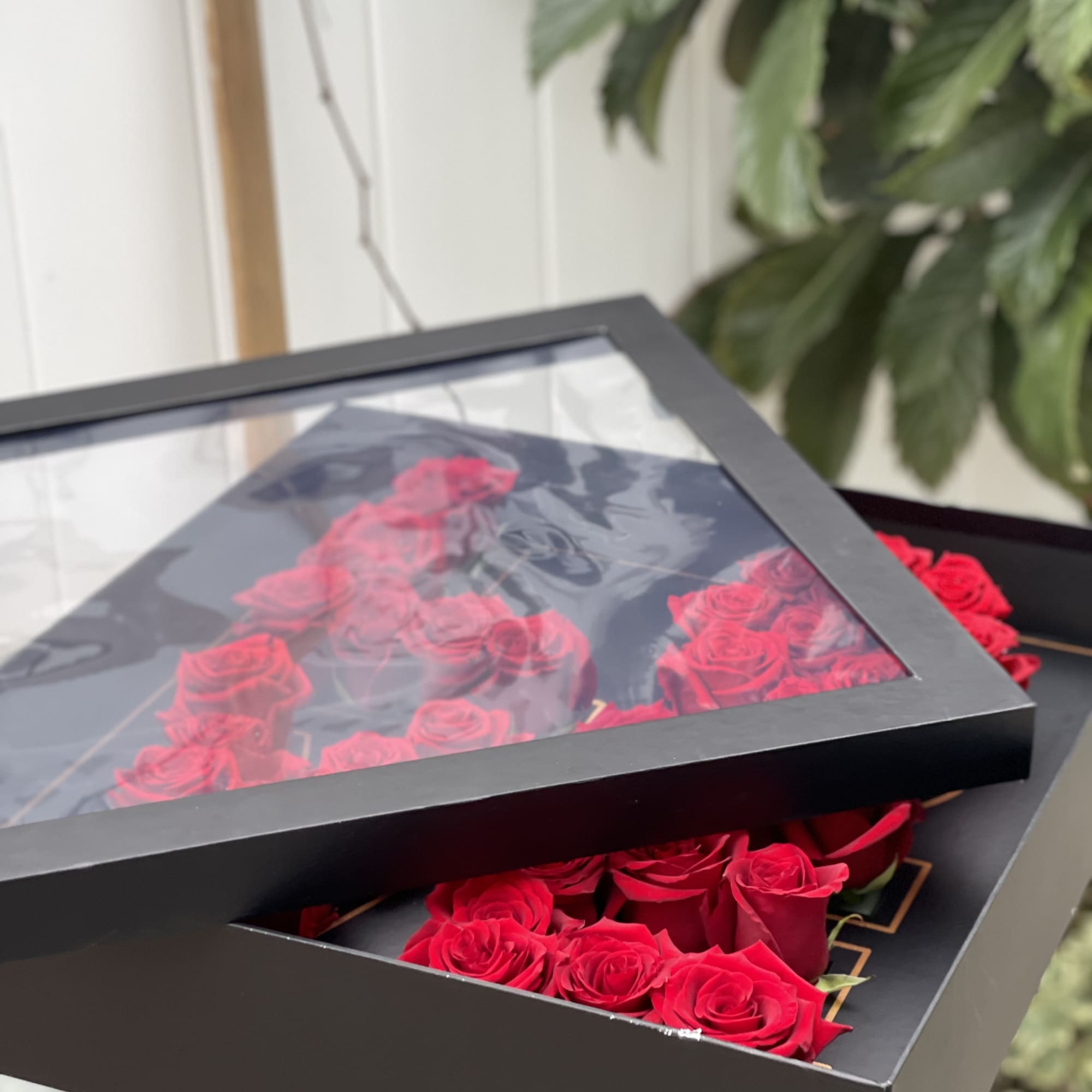 Red roses arranged in a black presentation box with a clear lid