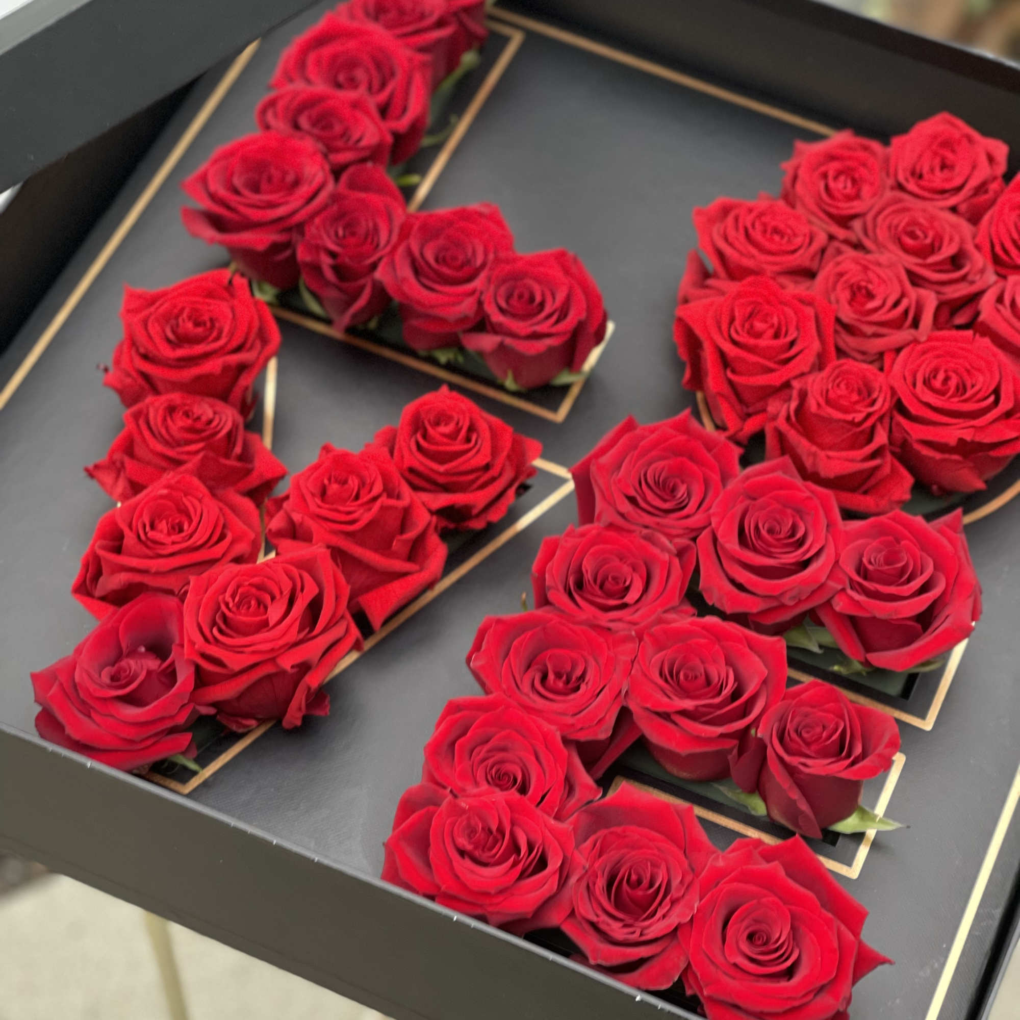 Red roses arranged in the shape of the number 50 in a black tray