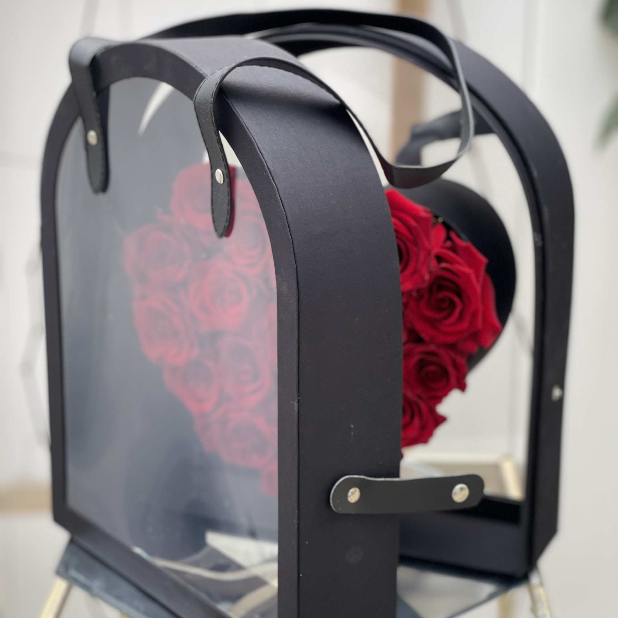 Red roses arranged in a black box with a clear front panel