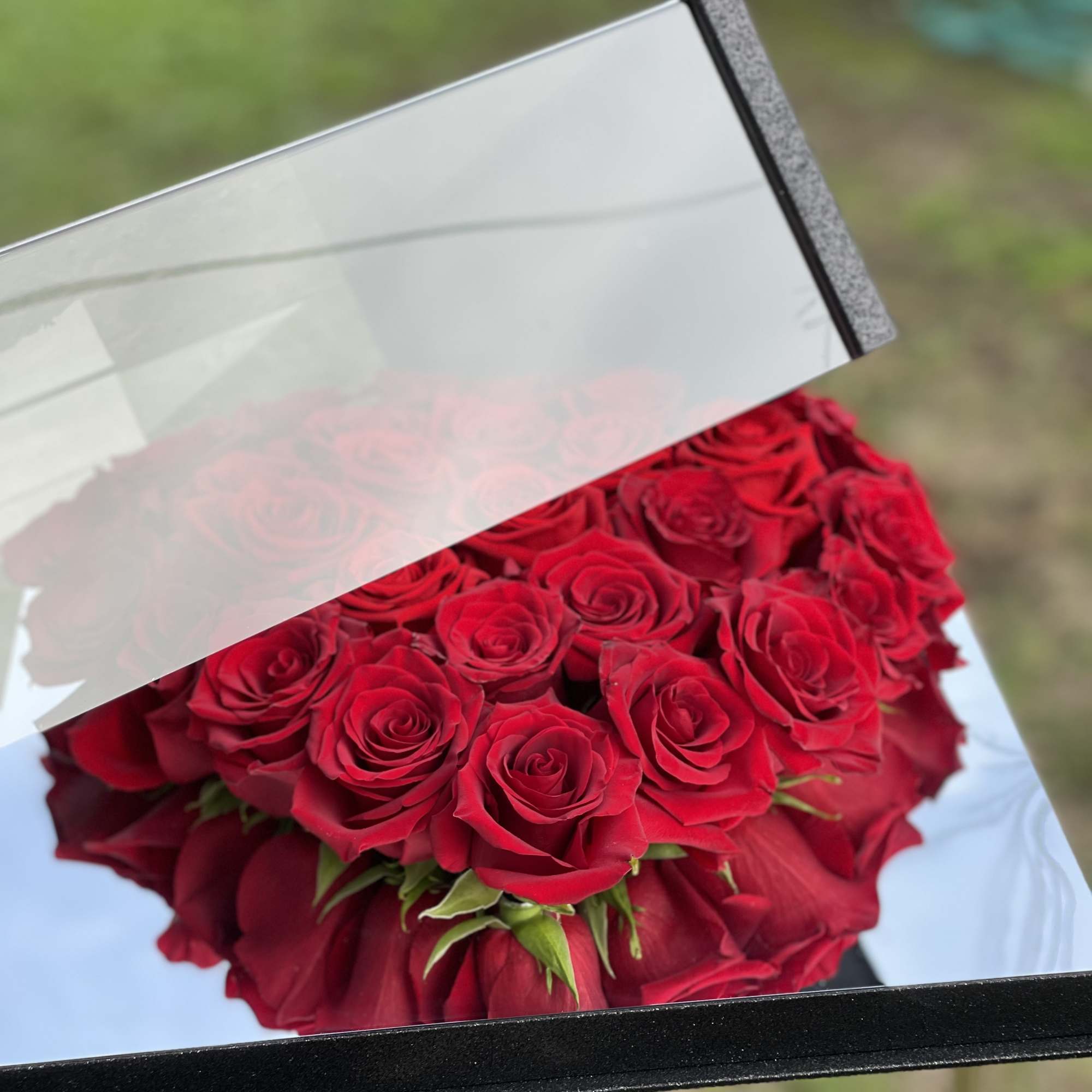 Bouquet of red roses in a black box with clear lid