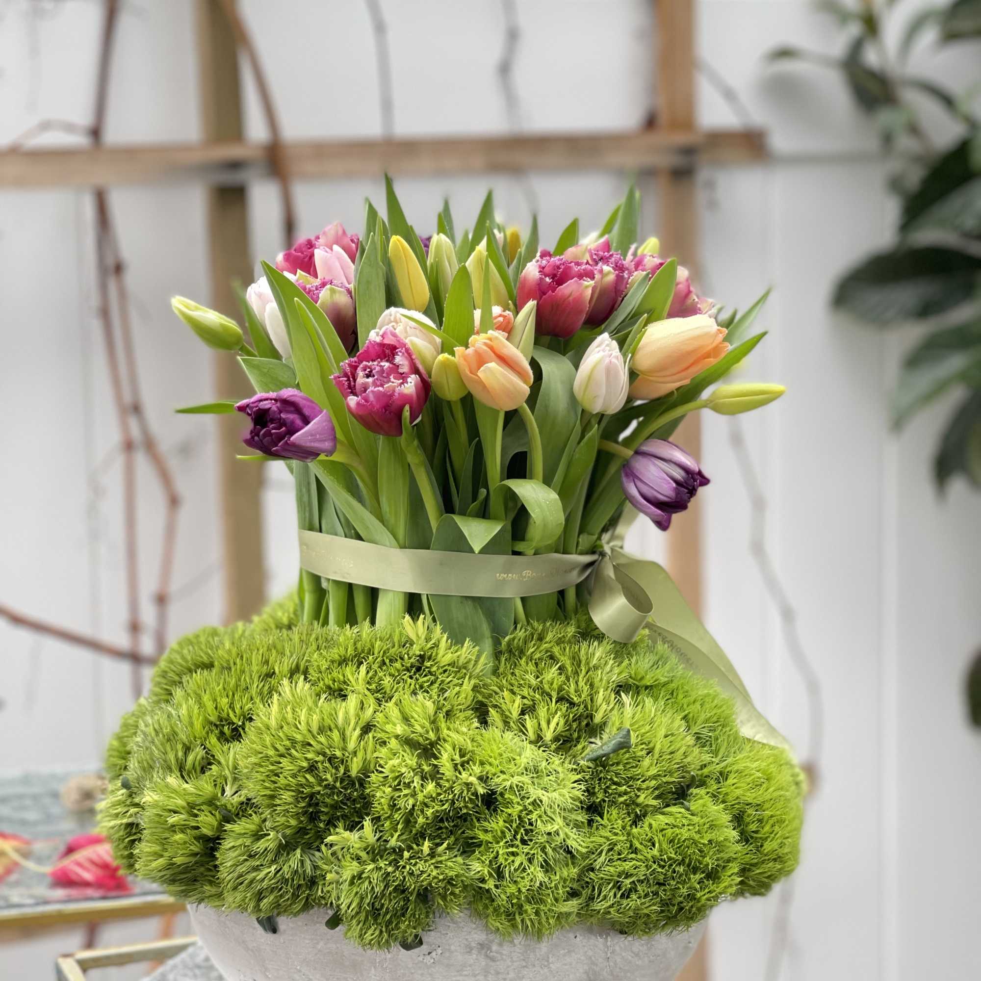 Bouquet of multicolored tulips in a round white bowl with green moss