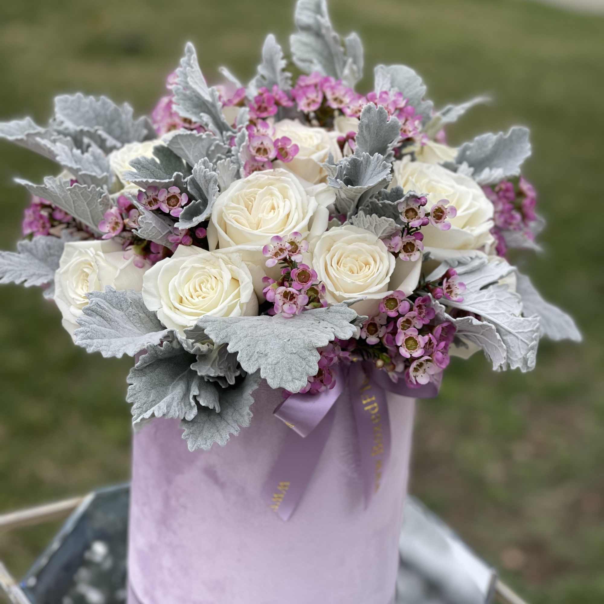 White roses and pink filler flowers in a lavender hat box