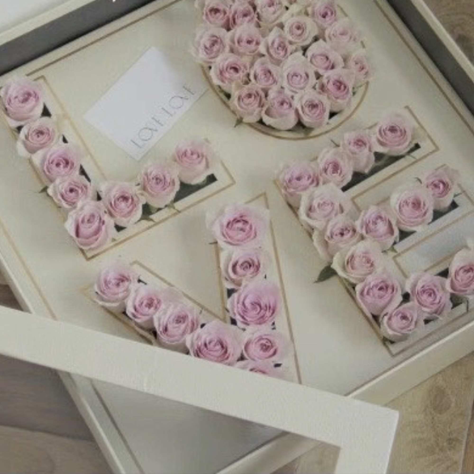 Pink roses arranged in a gift box to spell "LOVE"