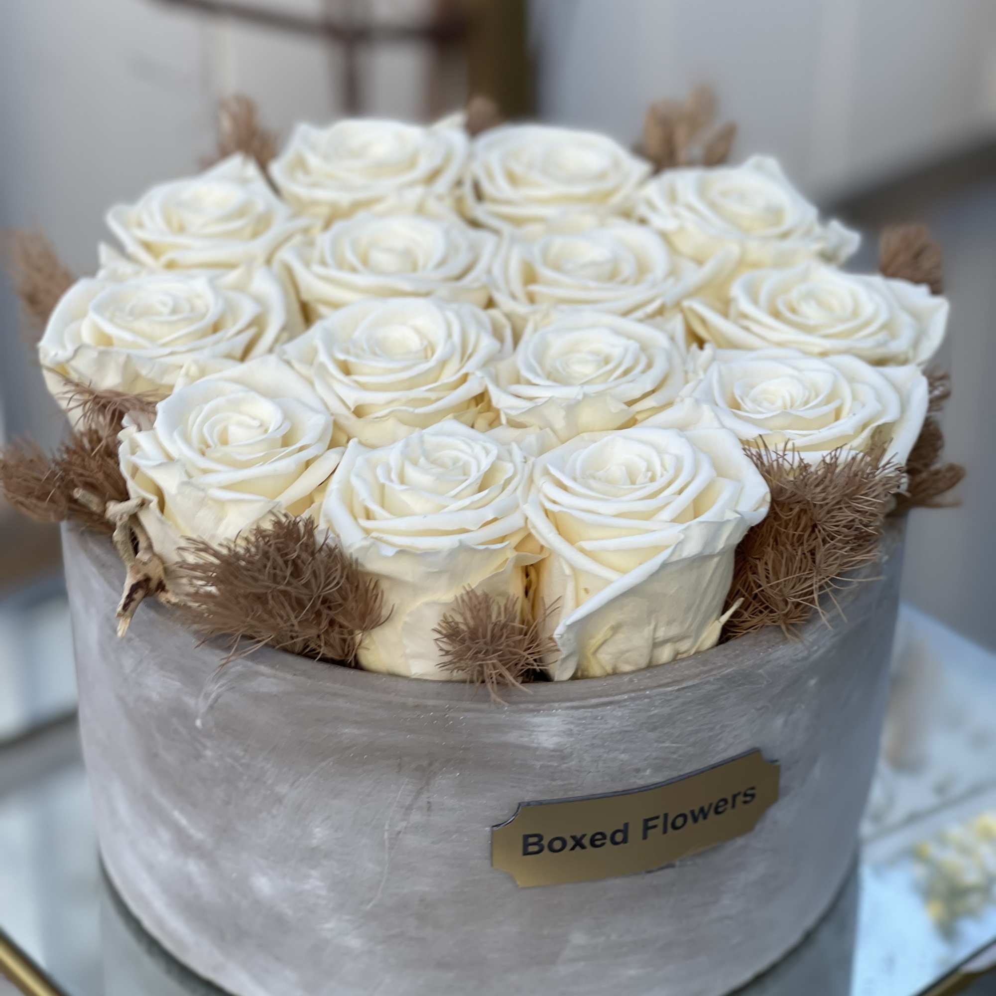 Boxed arrangement of white roses in a round container