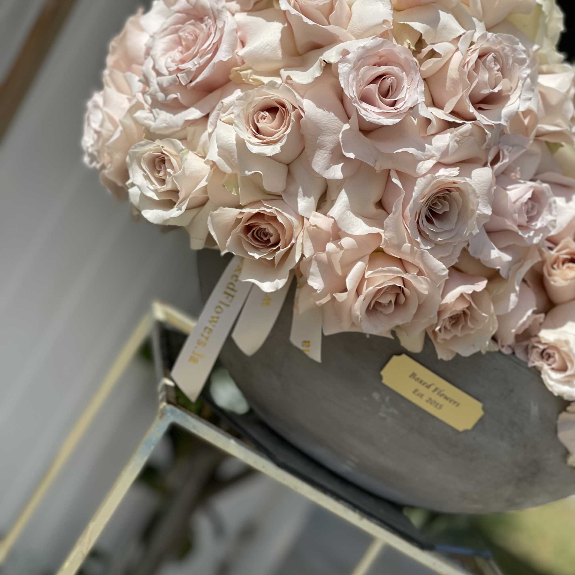 Bouquet of pale pink roses in a gray hatbox
