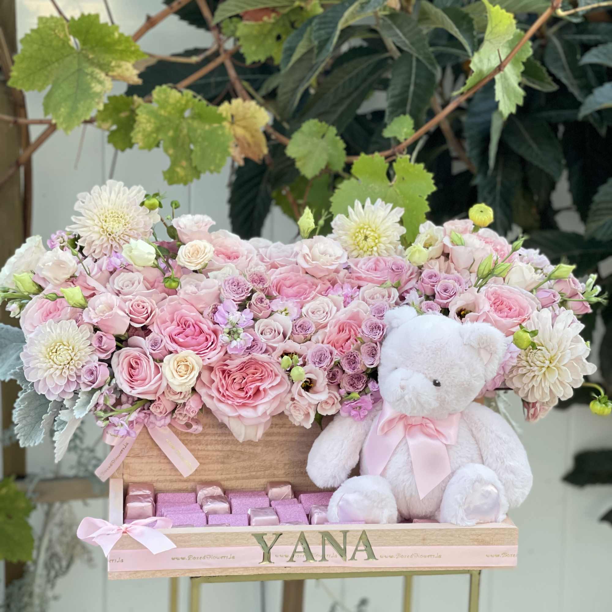 Pink rose arrangement in a wooden box with a white teddy bear and chocolates