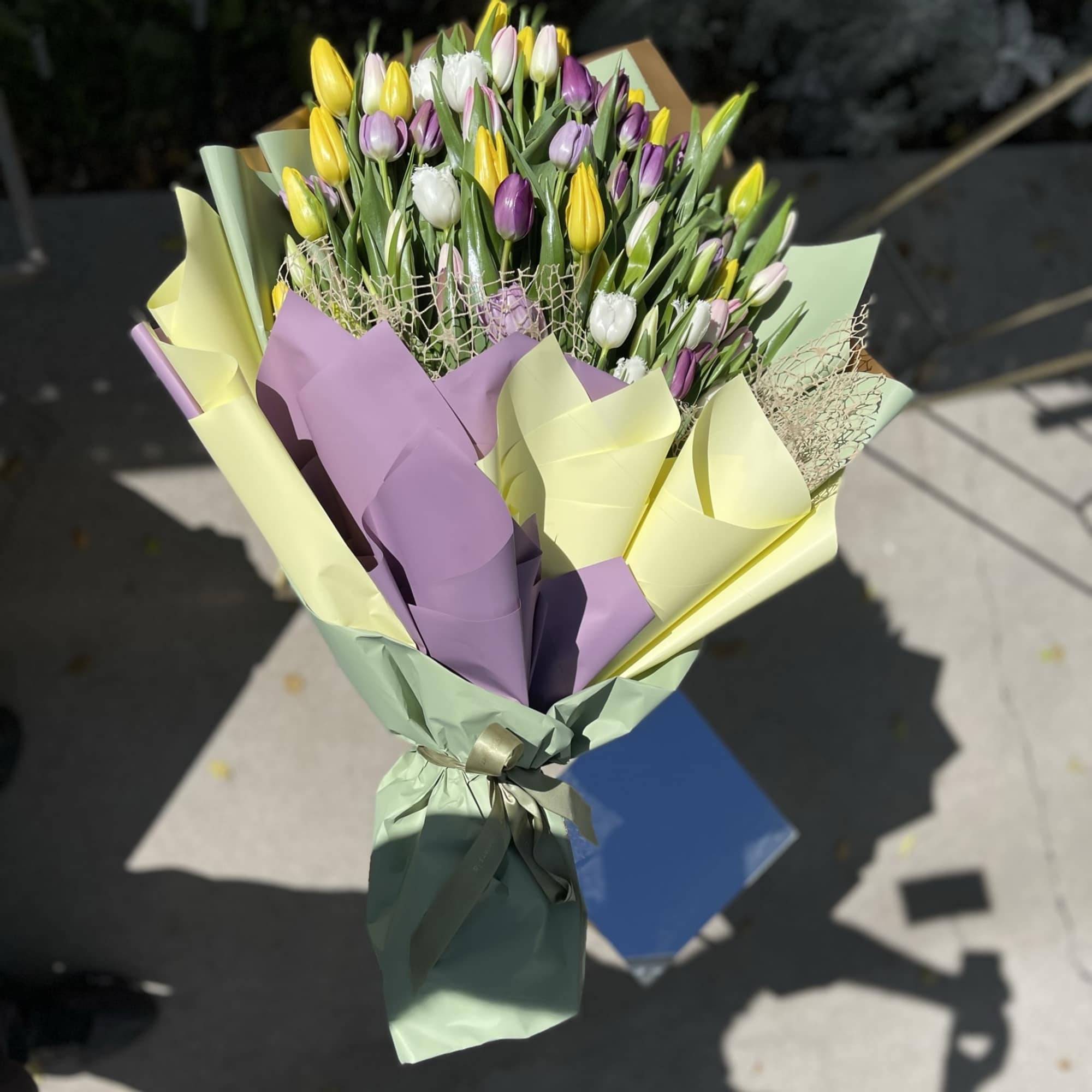 Bouquet of yellow, purple, and white tulips wrapped in pastel paper