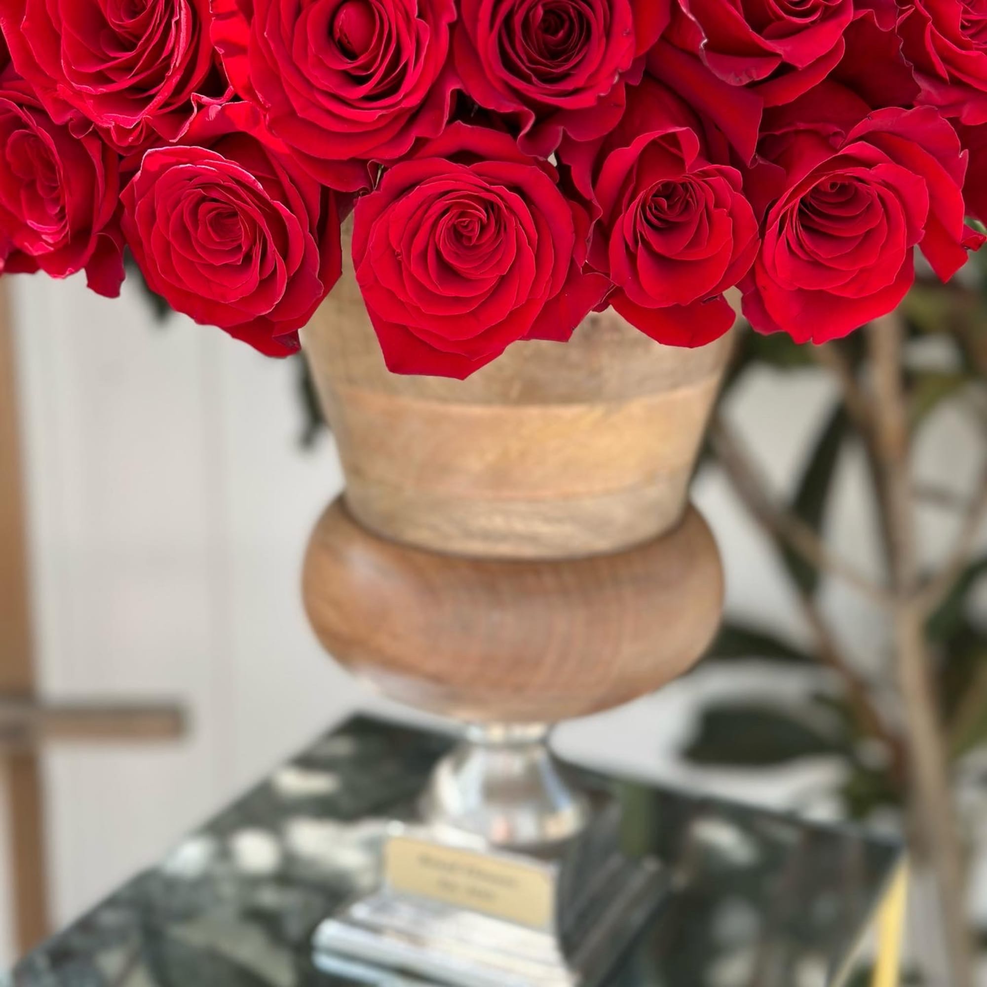 Red roses arranged in a gold pedestal vase