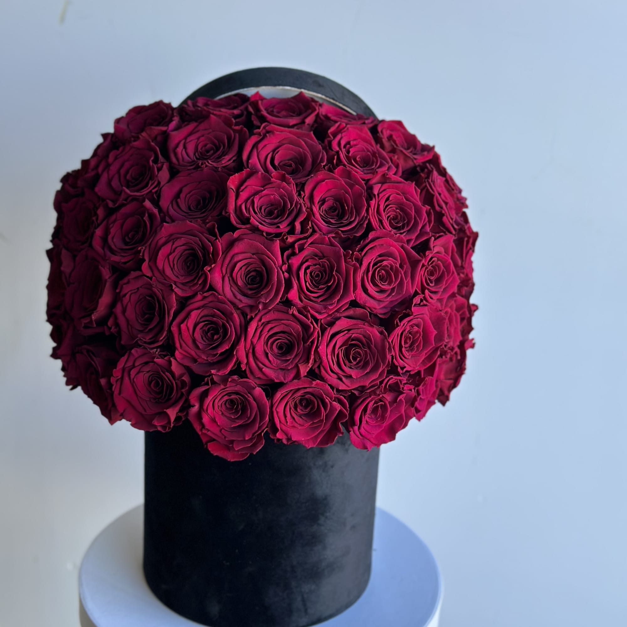 Round arrangement of deep pink roses in a black box
