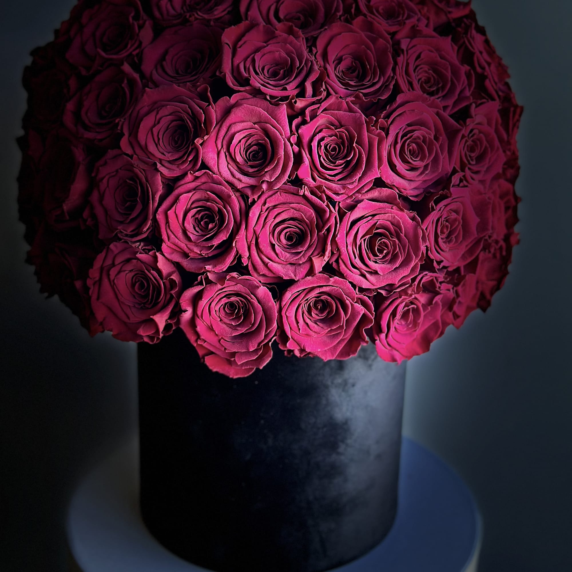 Round bouquet of deep pink roses in a black vase