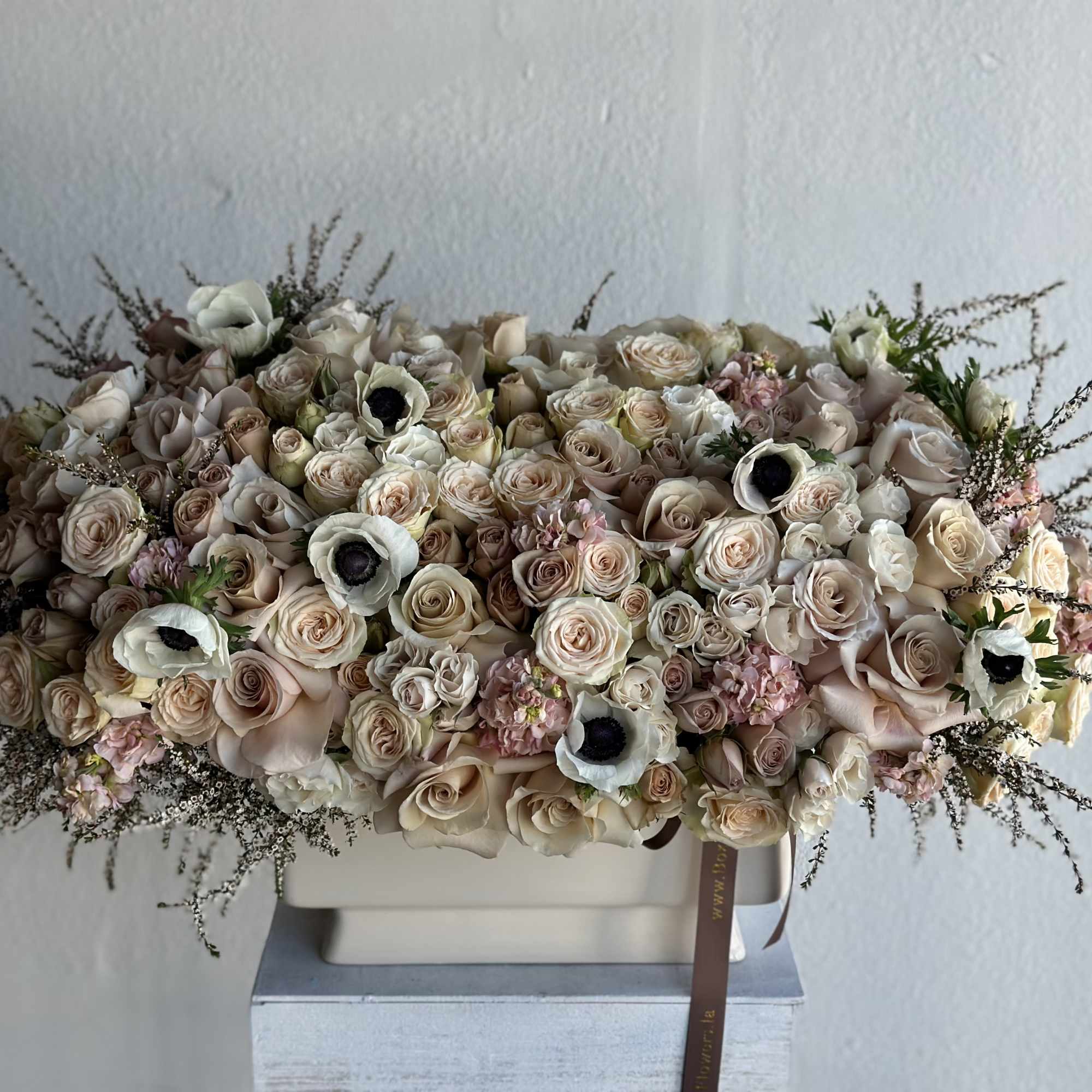 Large bouquet of blush and cream roses with white anemones in a rectangular vase
