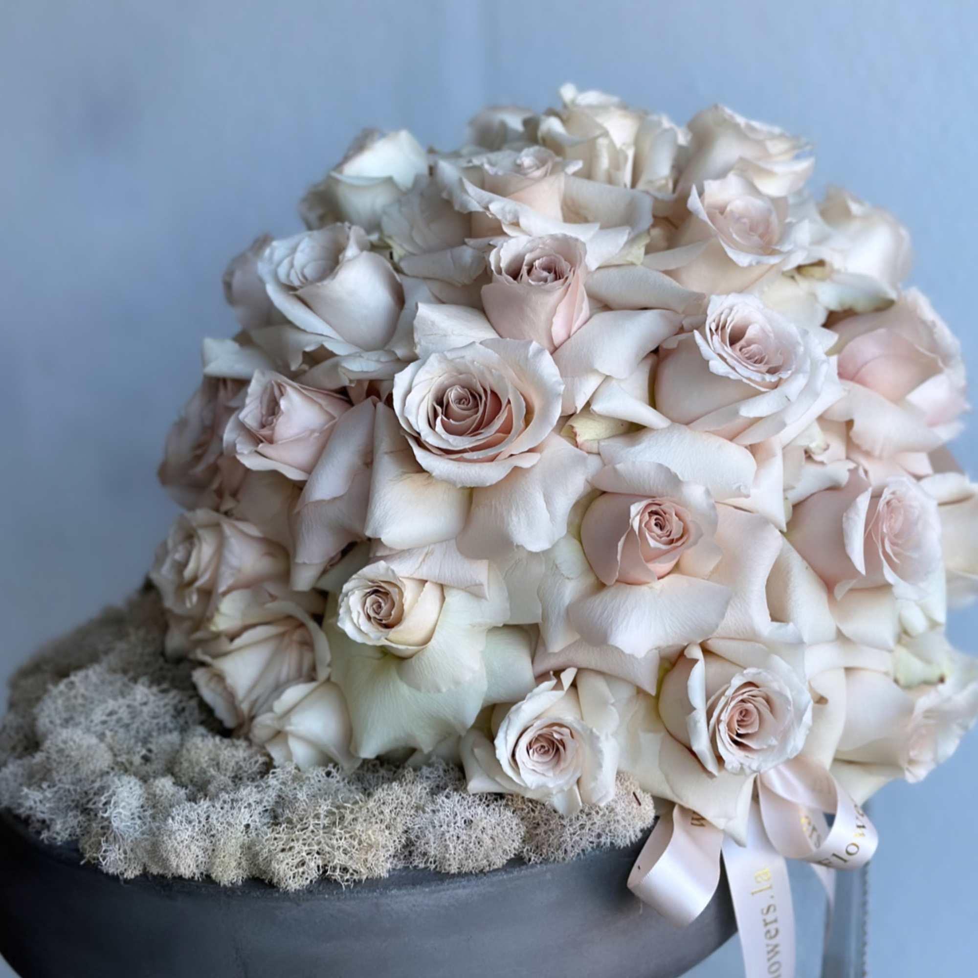 Round bouquet of pale blush and white roses in a black bowl
