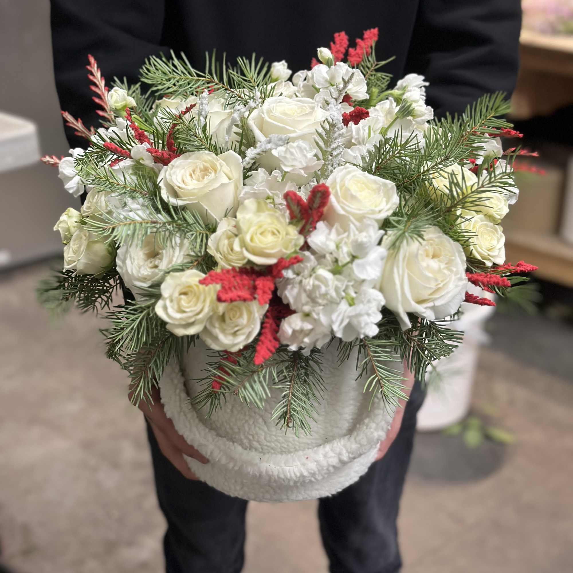 White rose bouquet with red accents in a white container