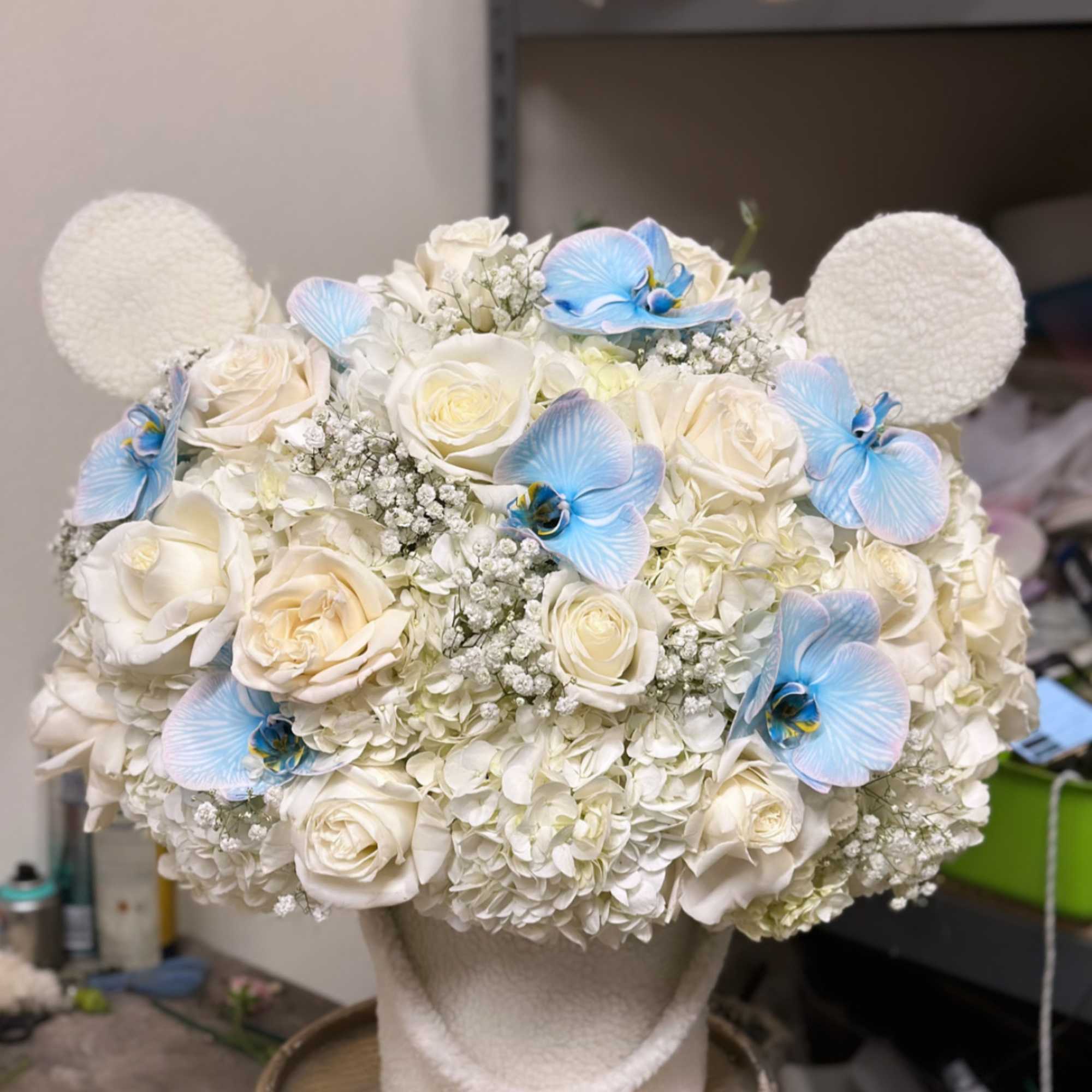 White rose and hydrangea arrangement with blue orchid accents in a textured vase