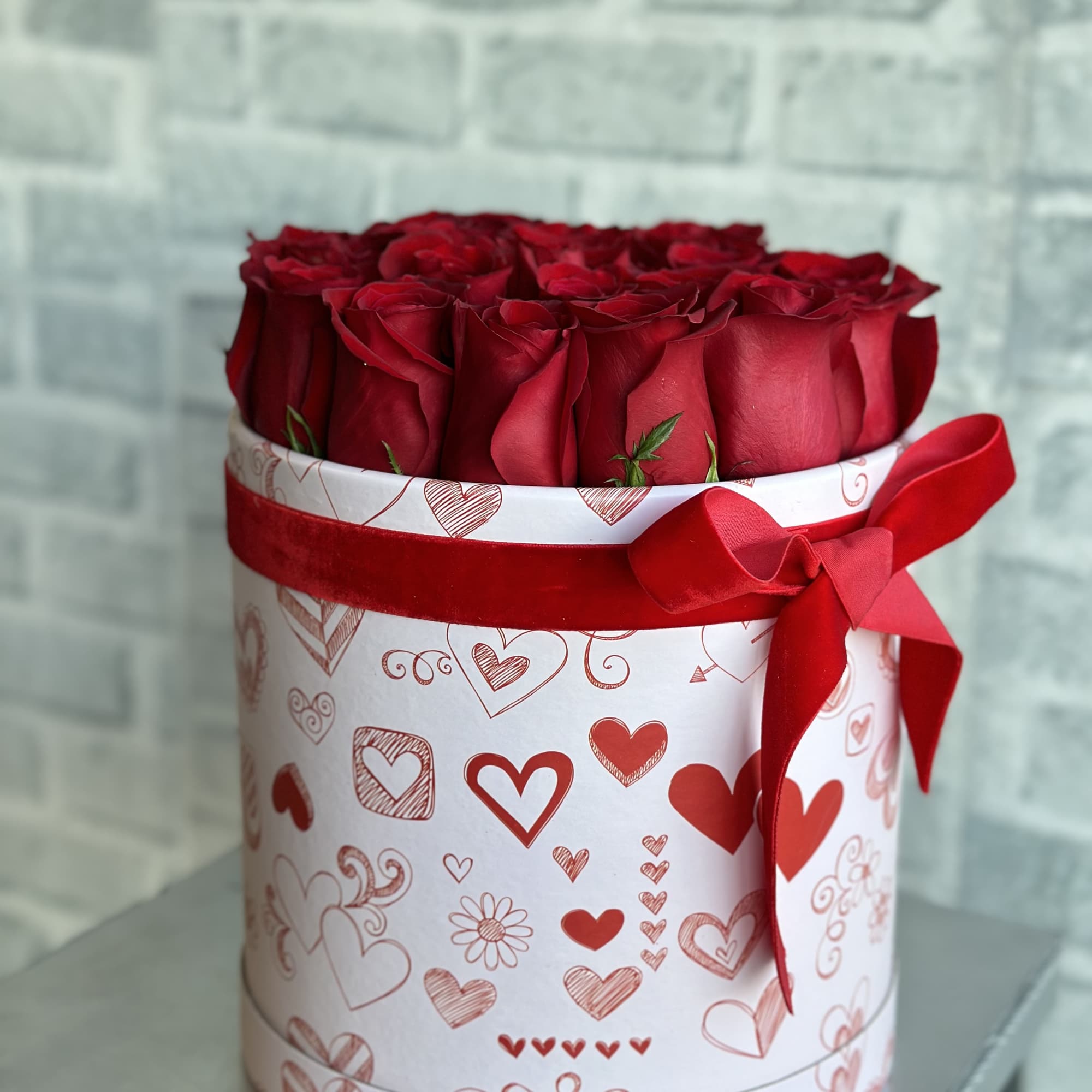 Red roses in a heart-patterned gift box with a red ribbon