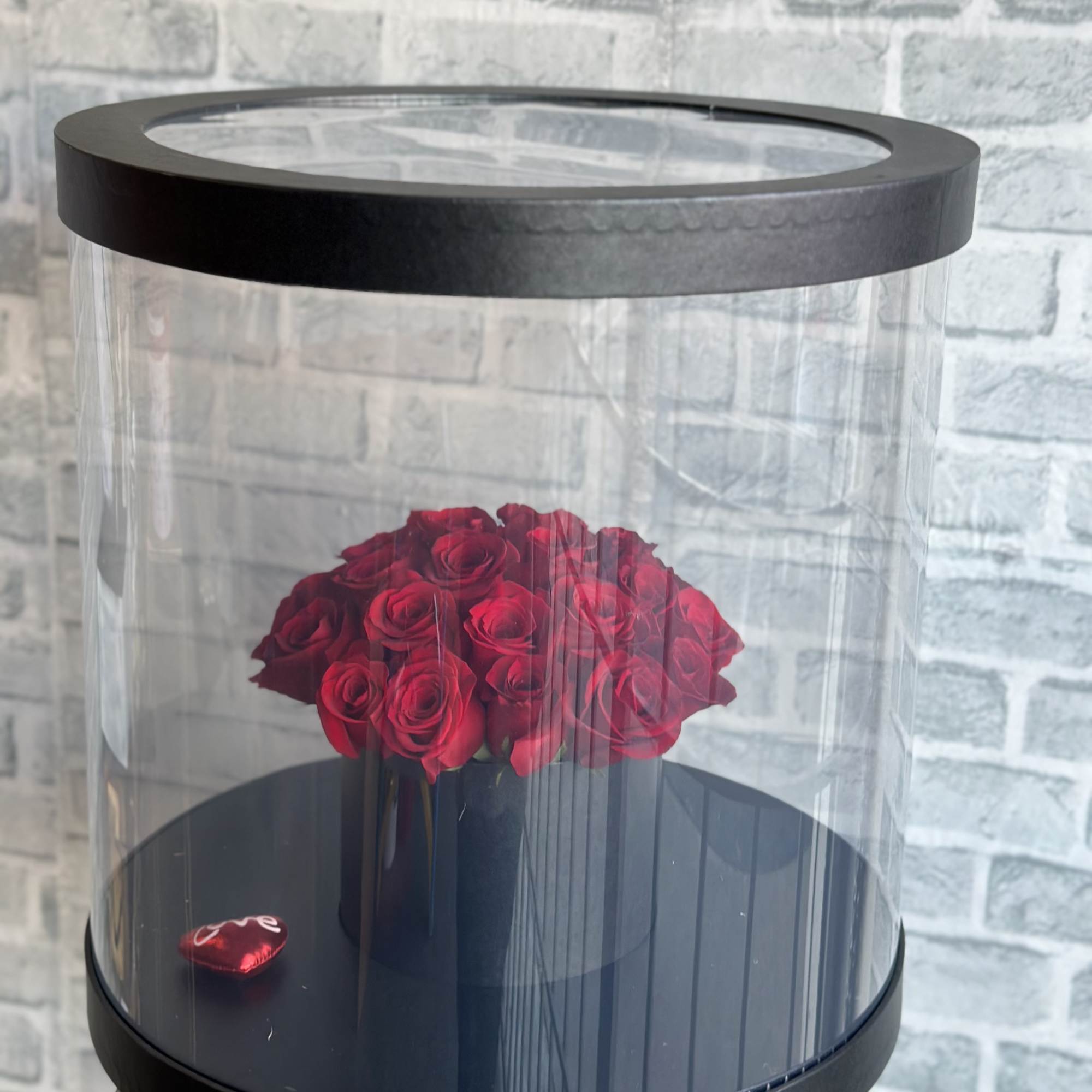 Red roses in a black round display box with a clear lid