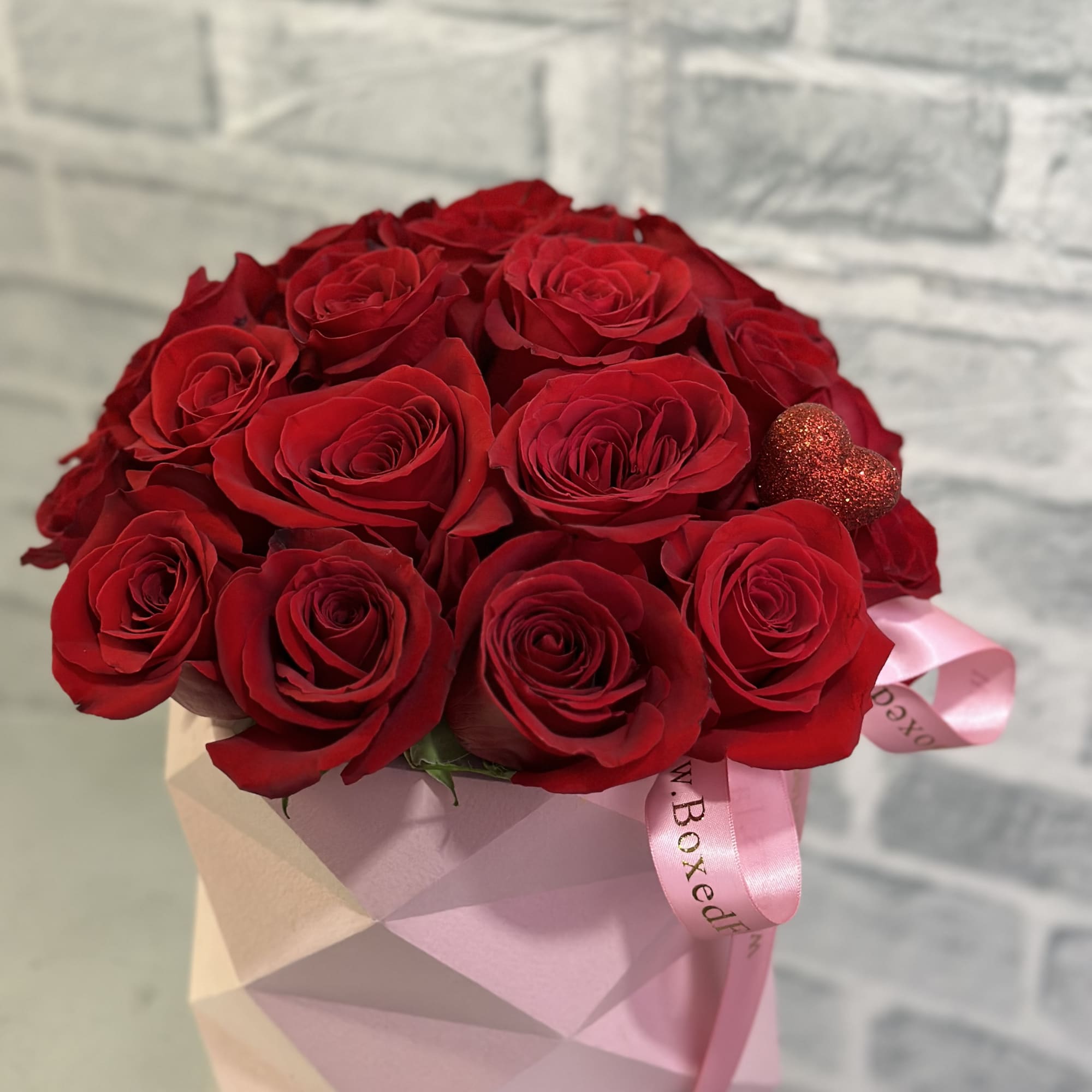 Red rose bouquet in a pink geometric box with a ribbon