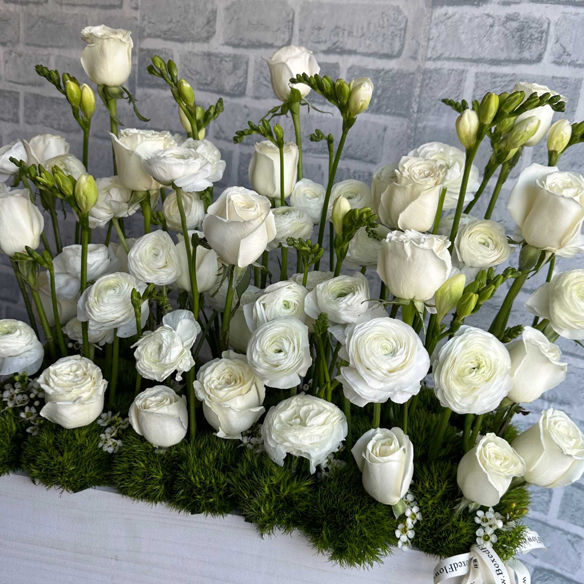 White roses and ranunculus arranged in a rectangular box