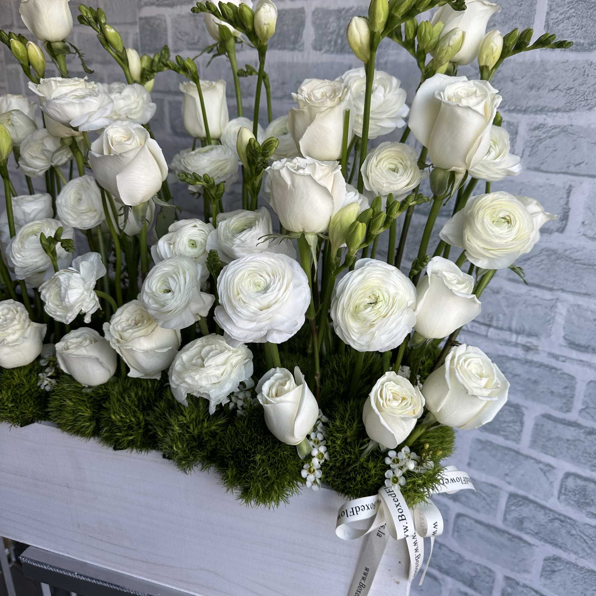 White roses and ranunculus arranged in a low rectangular box