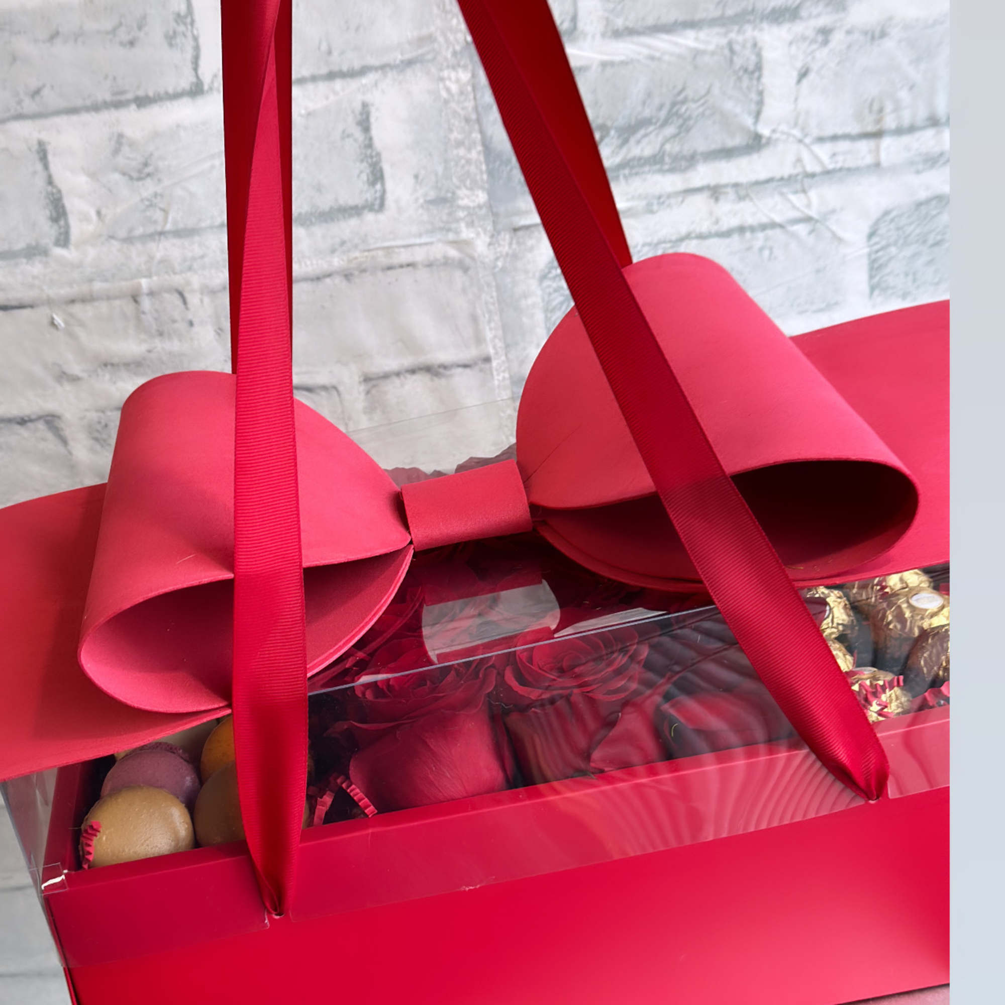 Red gift box with chocolates and a clear lid, tied with ribbon