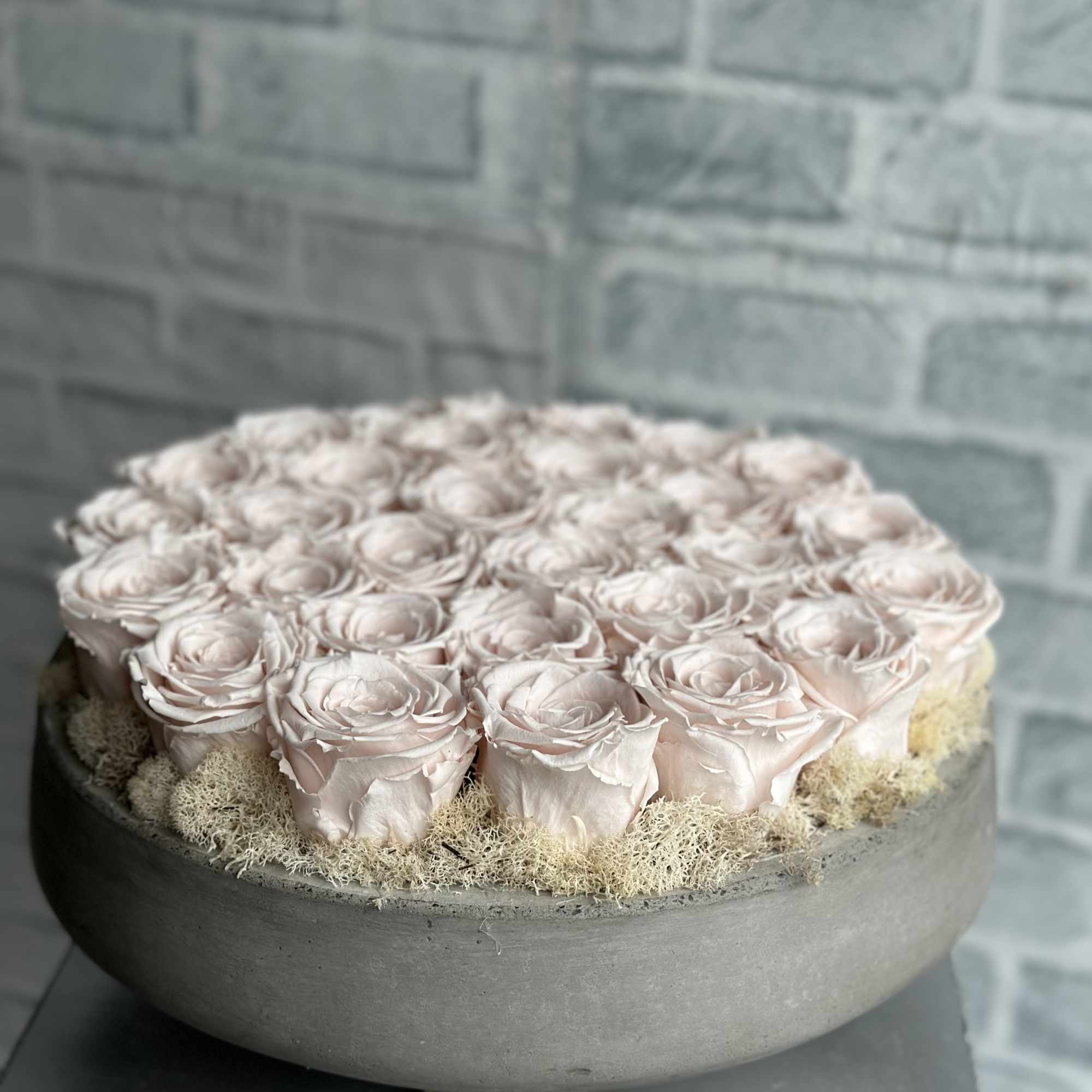 Round arrangement of pale pink roses in a gray bowl