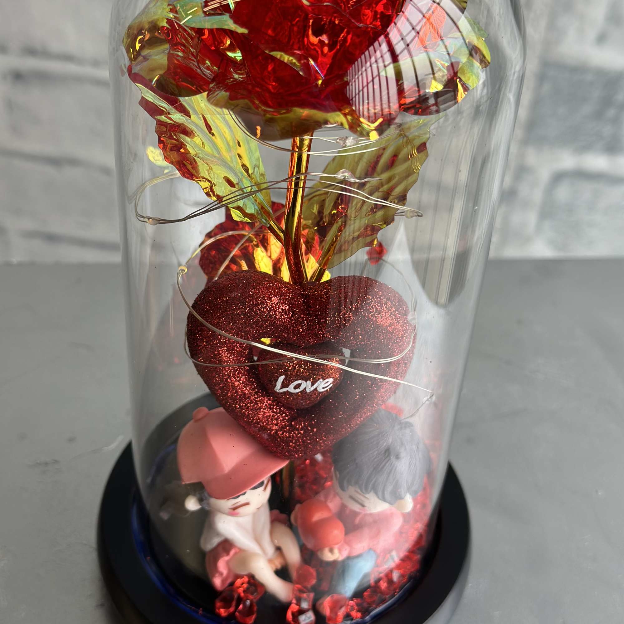 Decorative red heart display under a clear dome with two small figurines