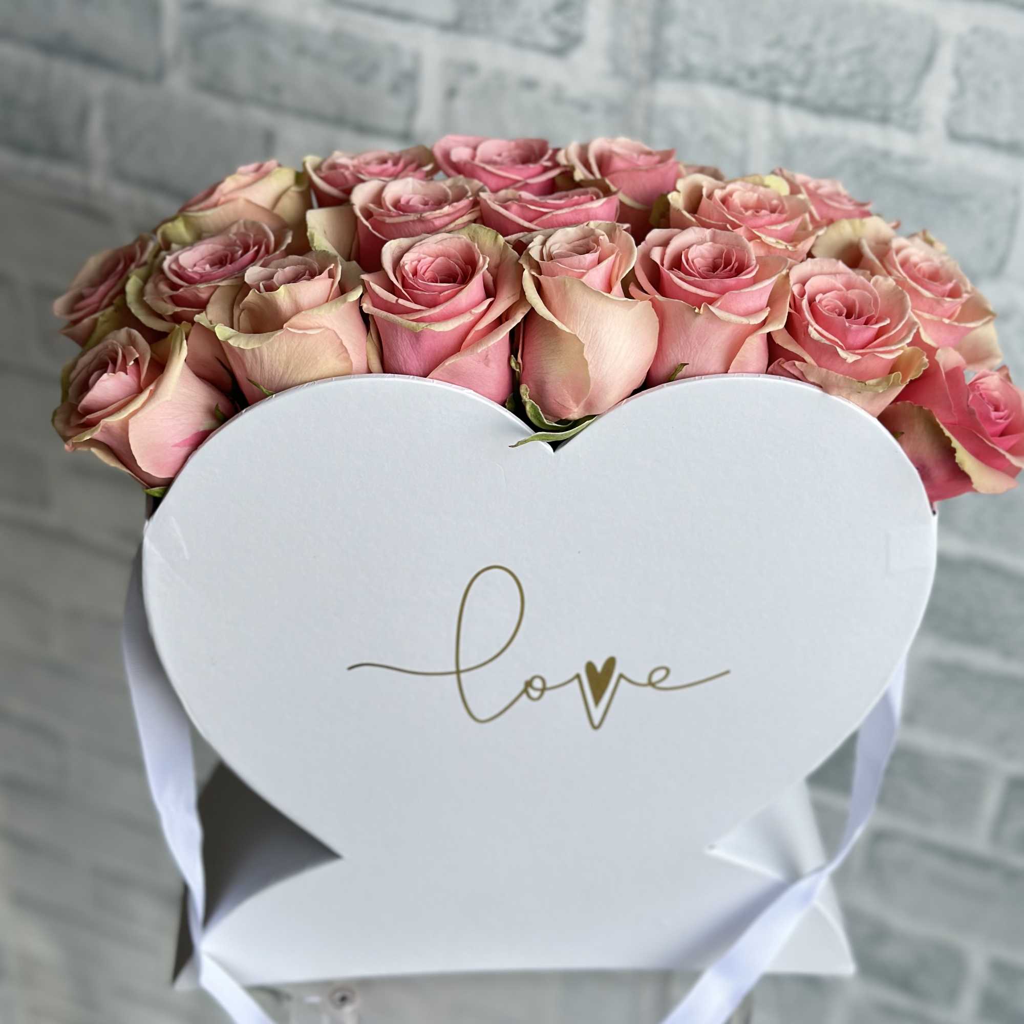 Pink roses in a white heart-shaped box with a "love" message