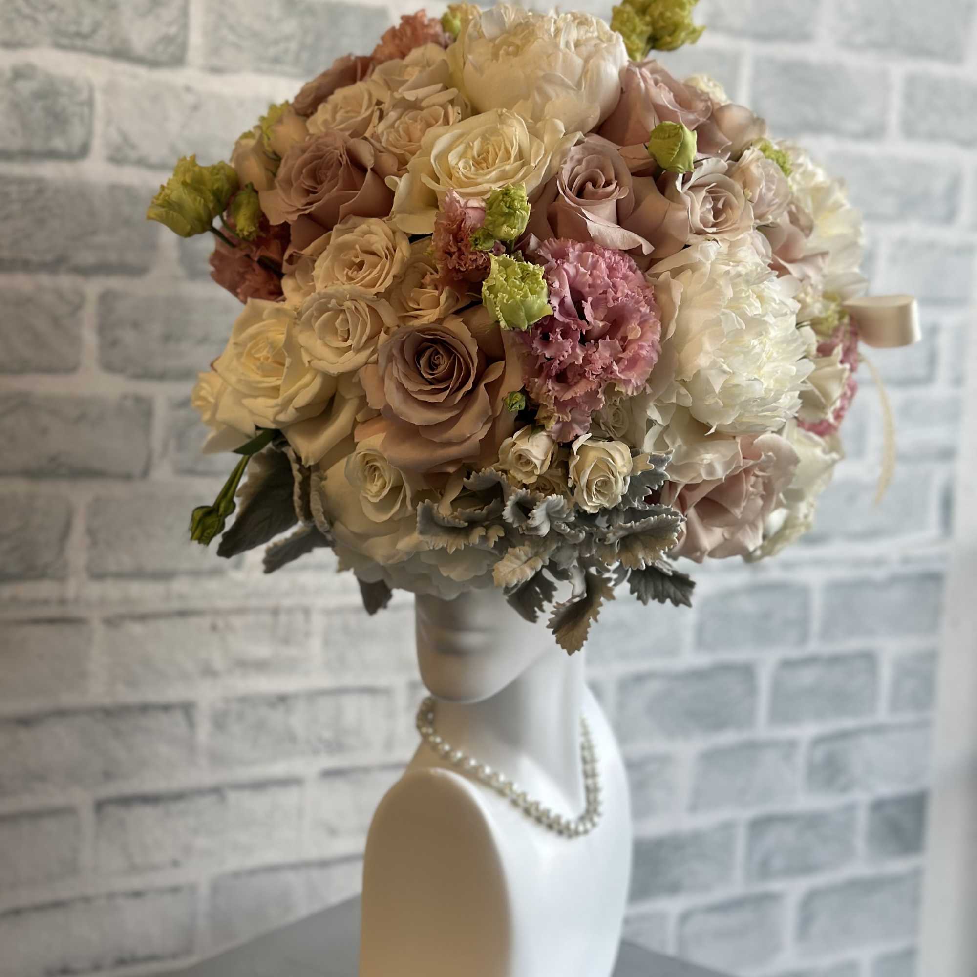 Bouquet of blush and cream roses with pink blooms on a mannequin bust