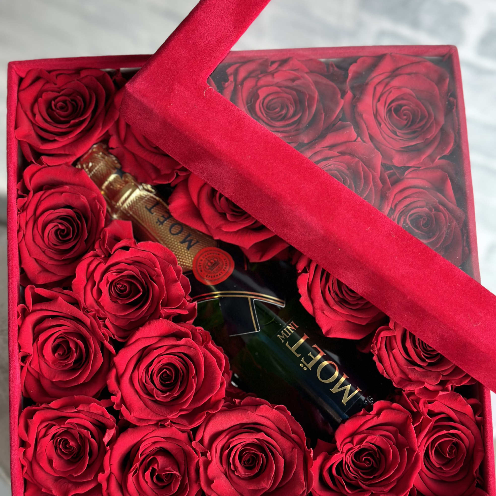 Box of red roses with a champagne bottle inside