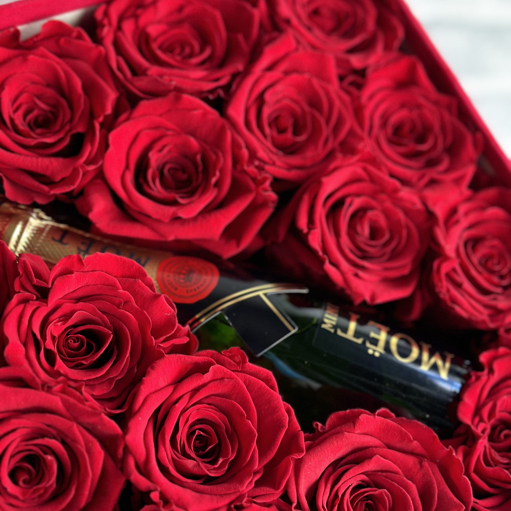 Box of red roses with a bottle of champagne
