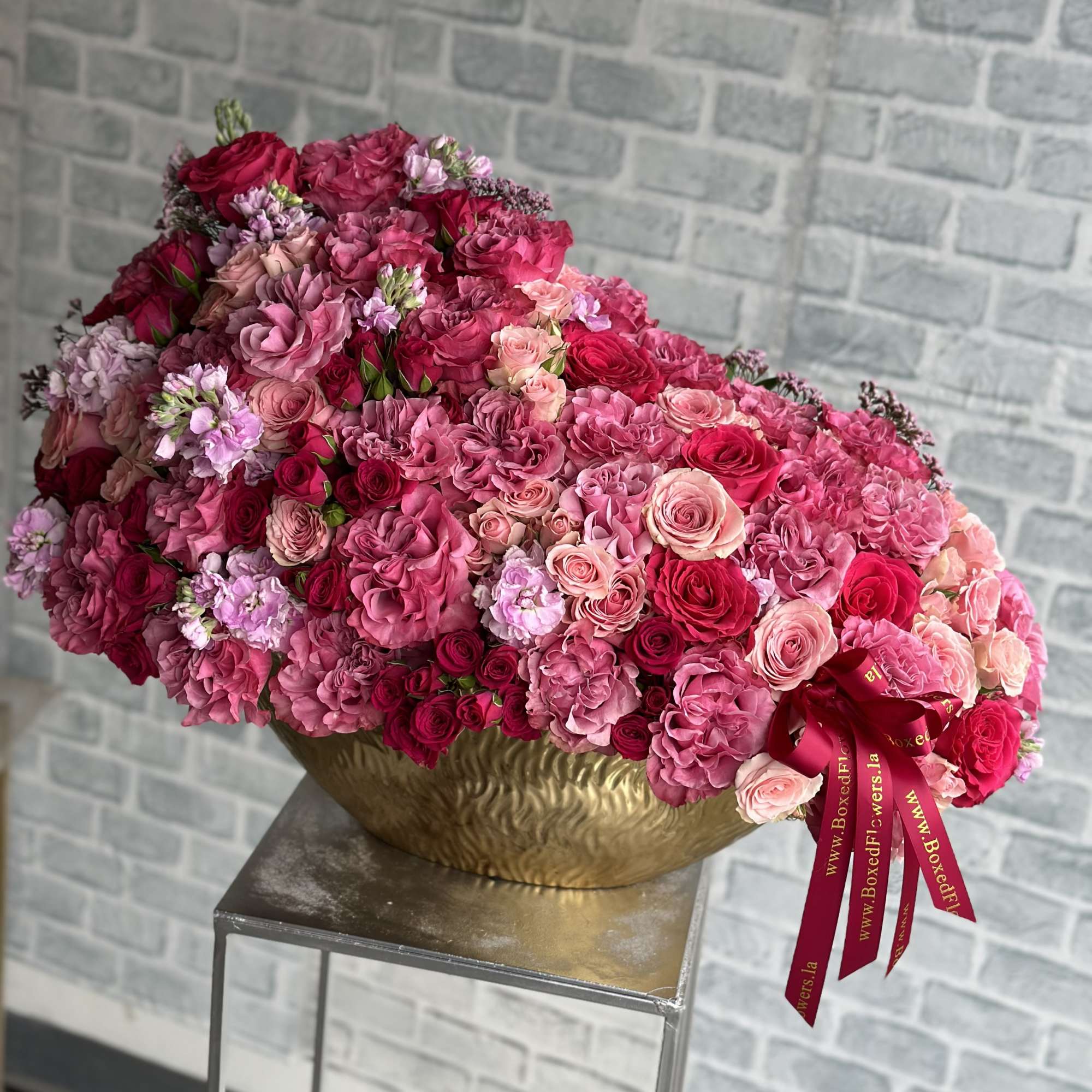 Large pink and red rose arrangement in a gold bowl