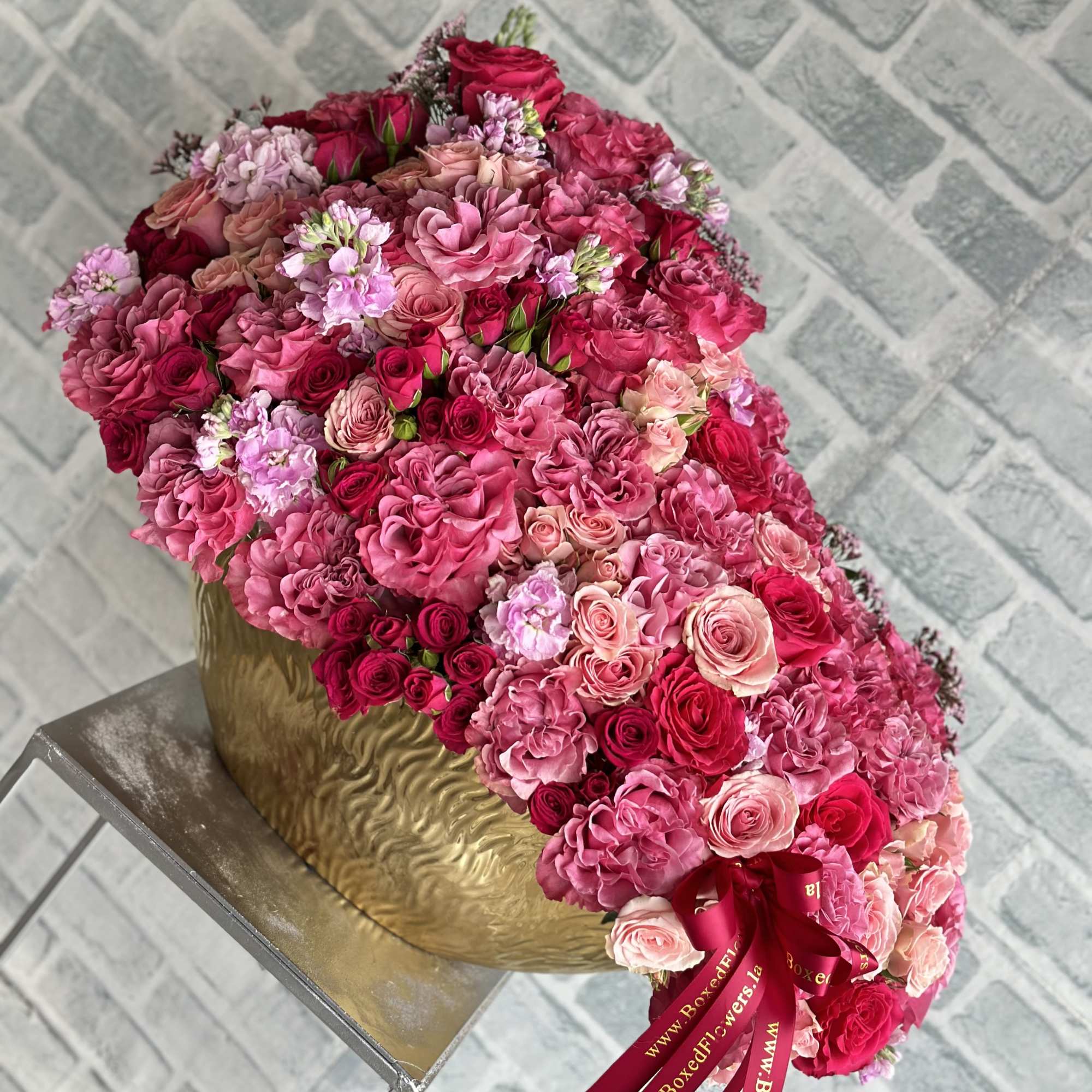 Cascade bouquet of pink and red roses in a gold vase