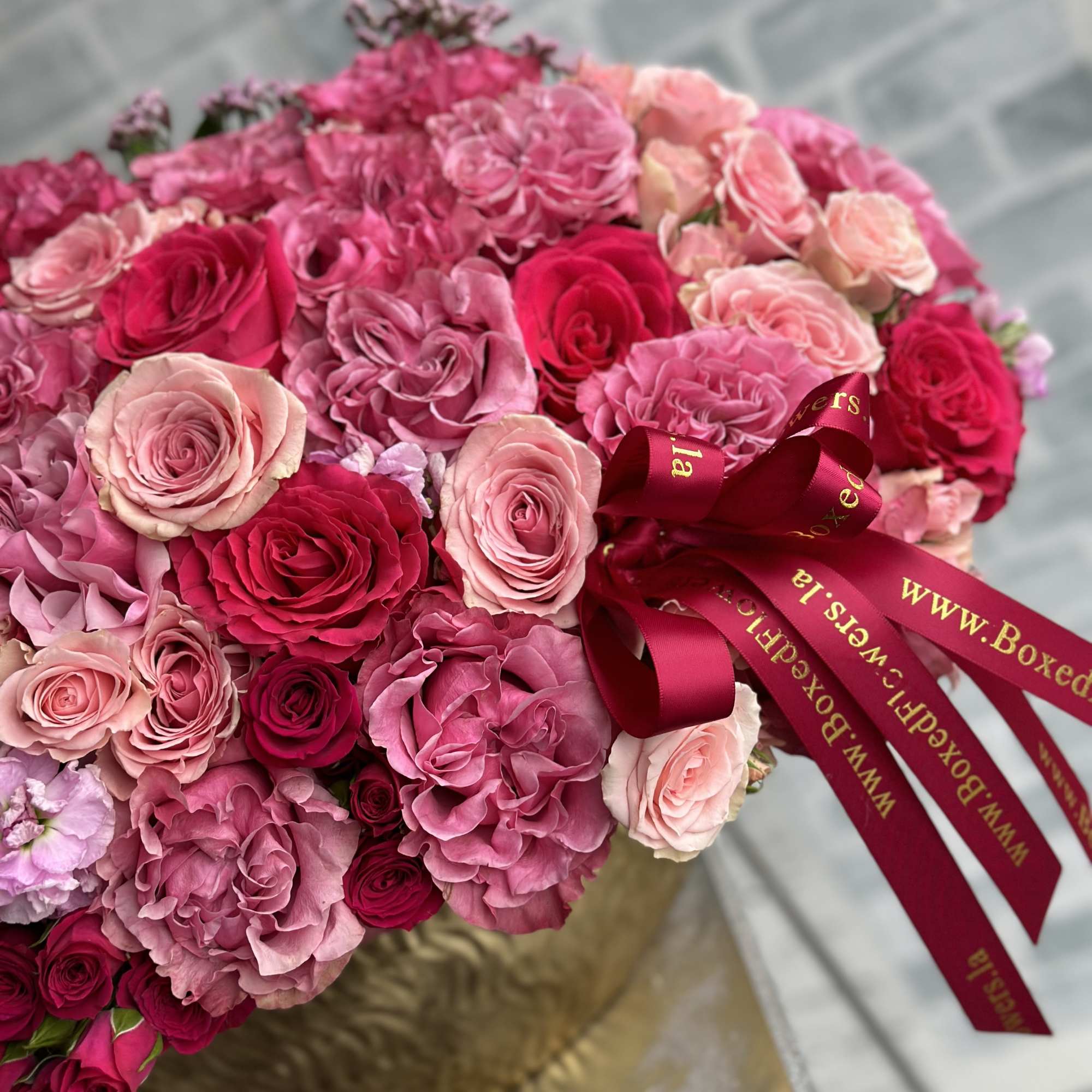 Round bouquet of pink and red roses with a burgundy ribbon