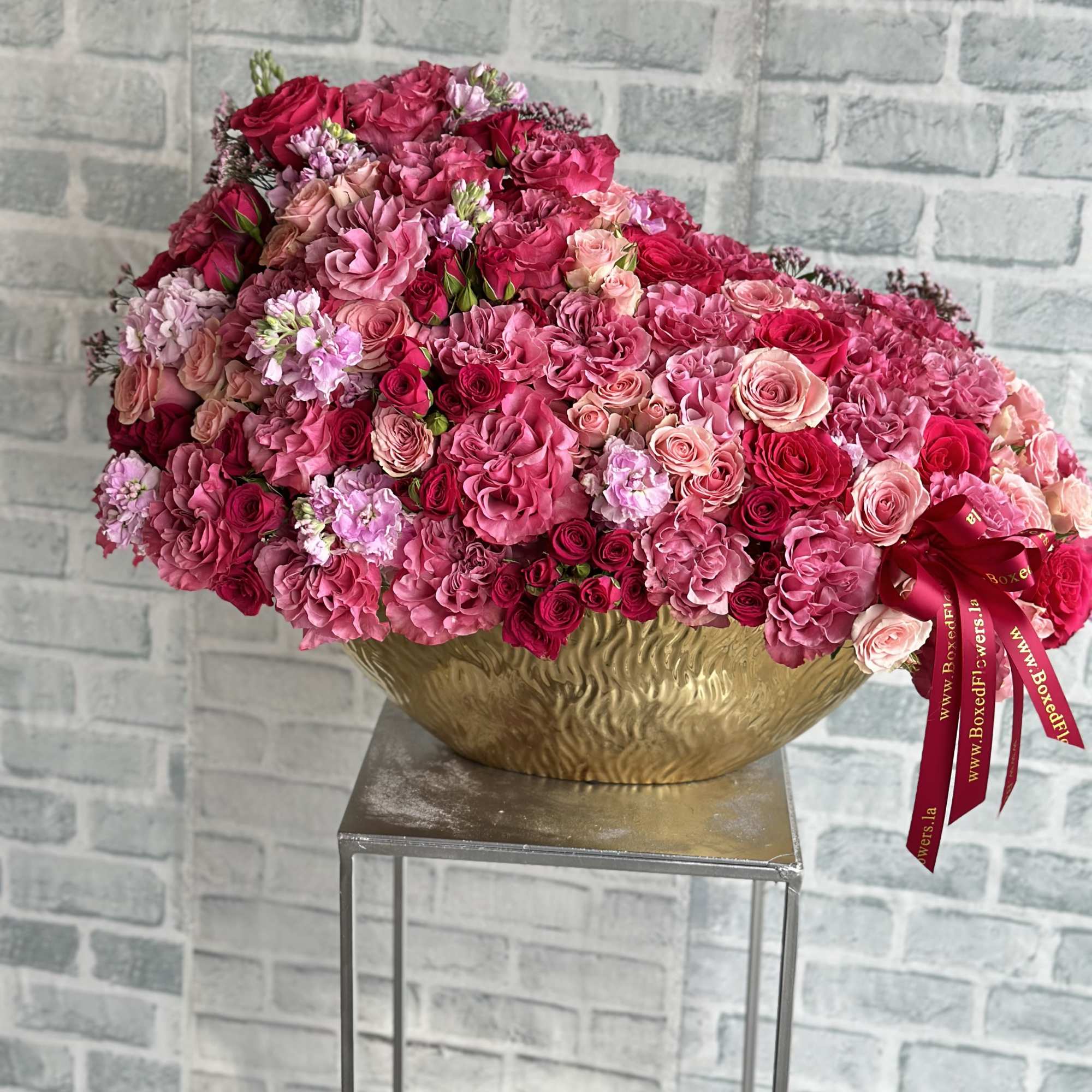 Large pink rose arrangement in a gold bowl on a stand