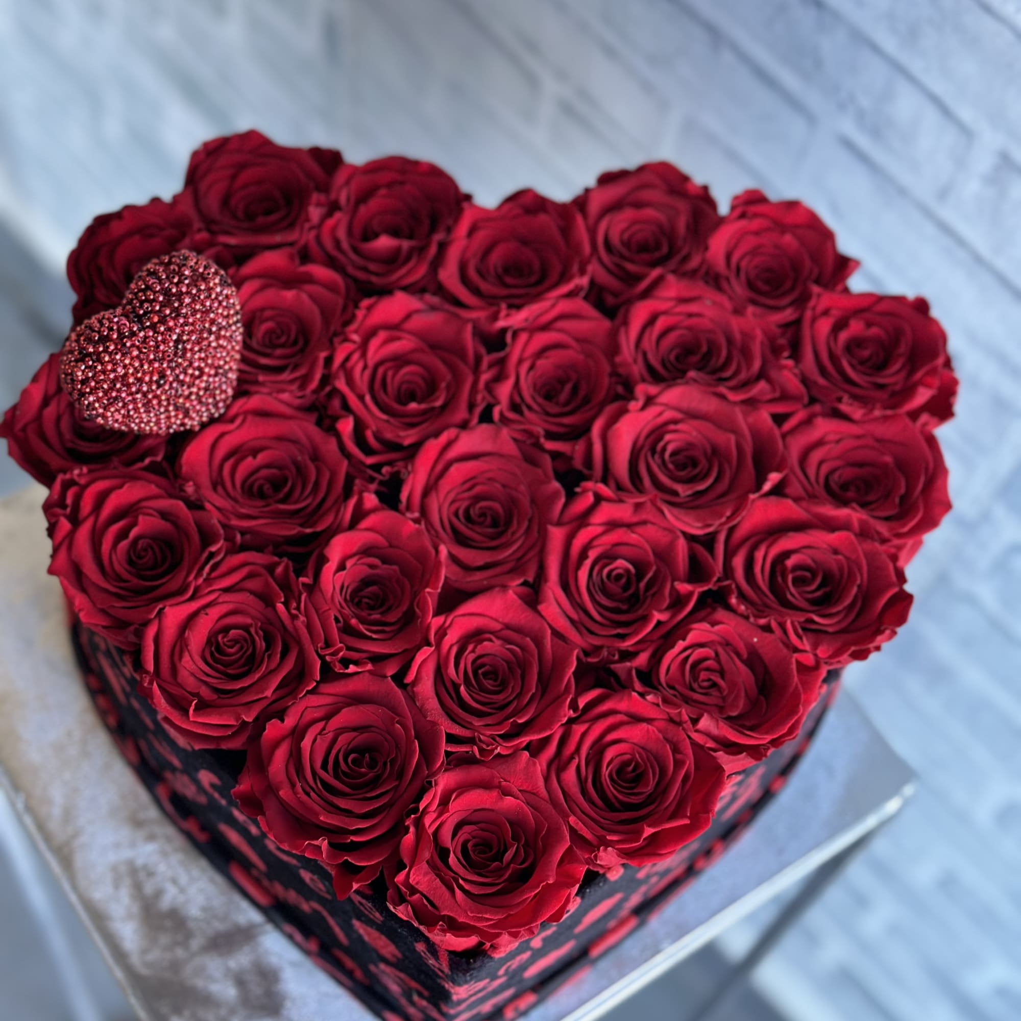 Heart-shaped box filled with red roses and a glittery heart accent