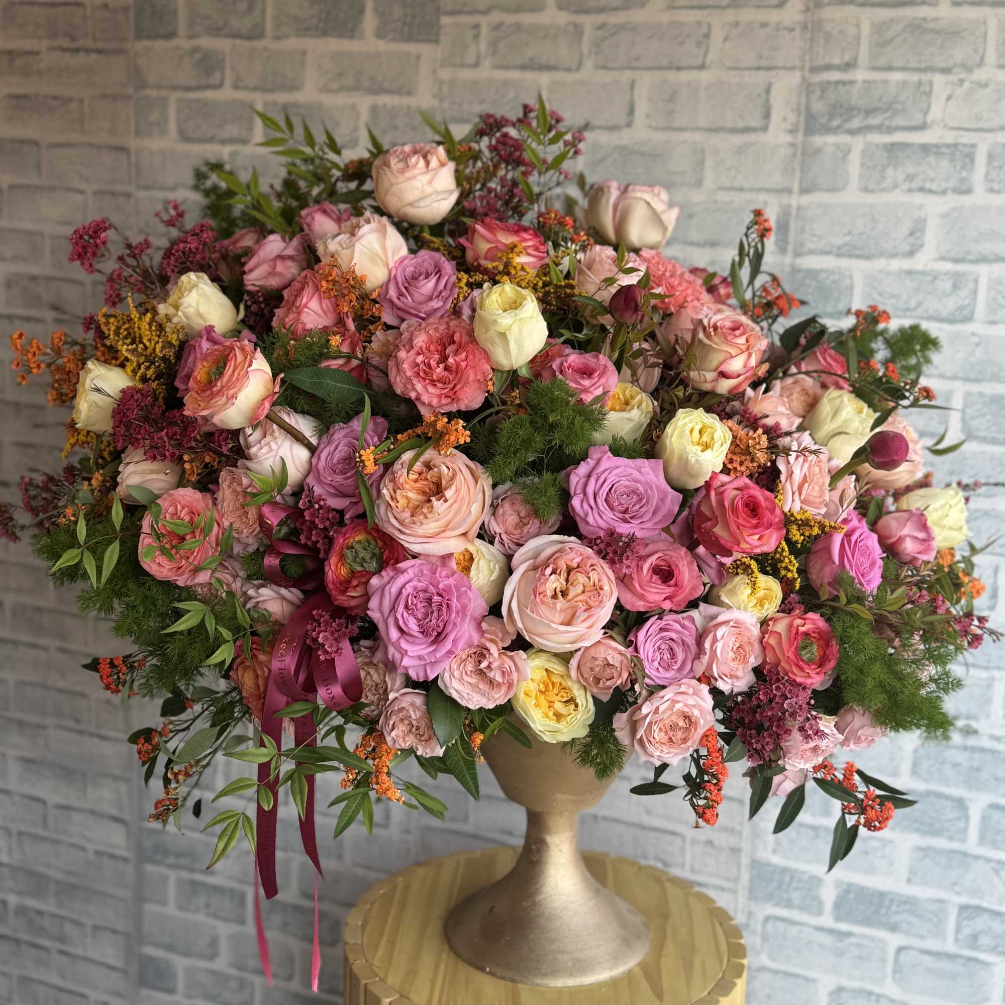 Large pastel bouquet of pink and peach roses in a gold pedestal vase