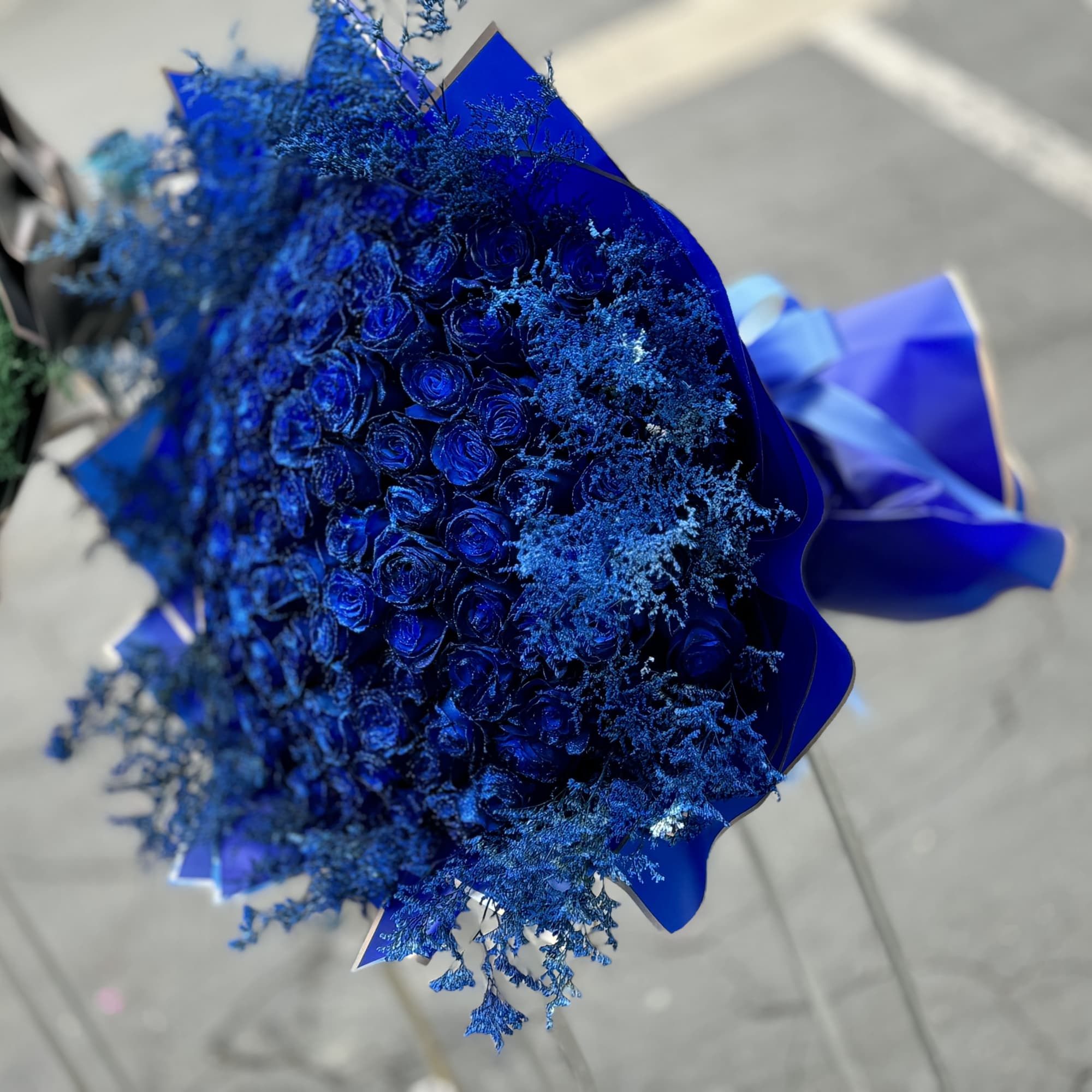 Bouquet of blue roses wrapped in blue paper with a ribbon