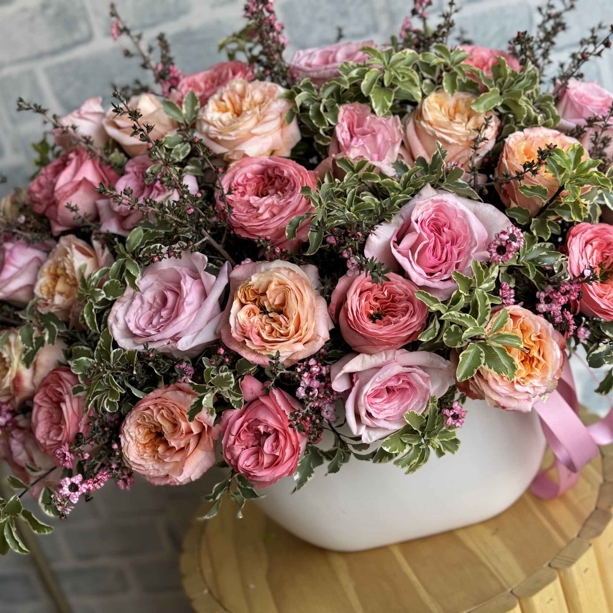 Pink and peach roses arranged in a white vase
