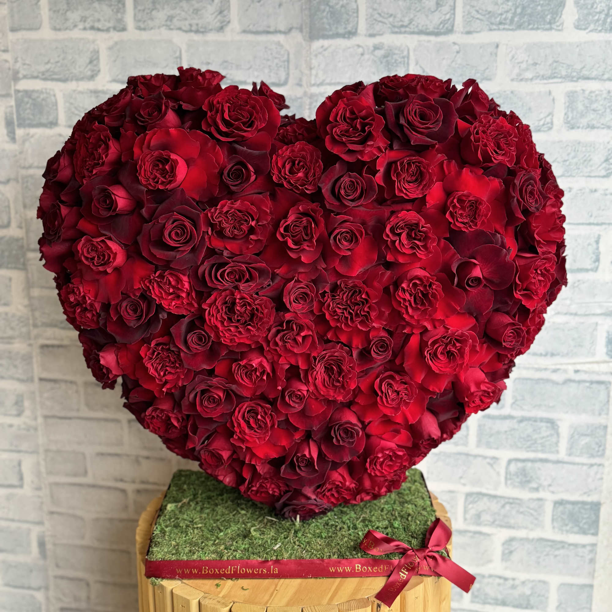 Heart-shaped arrangement of red roses on a wooden stand