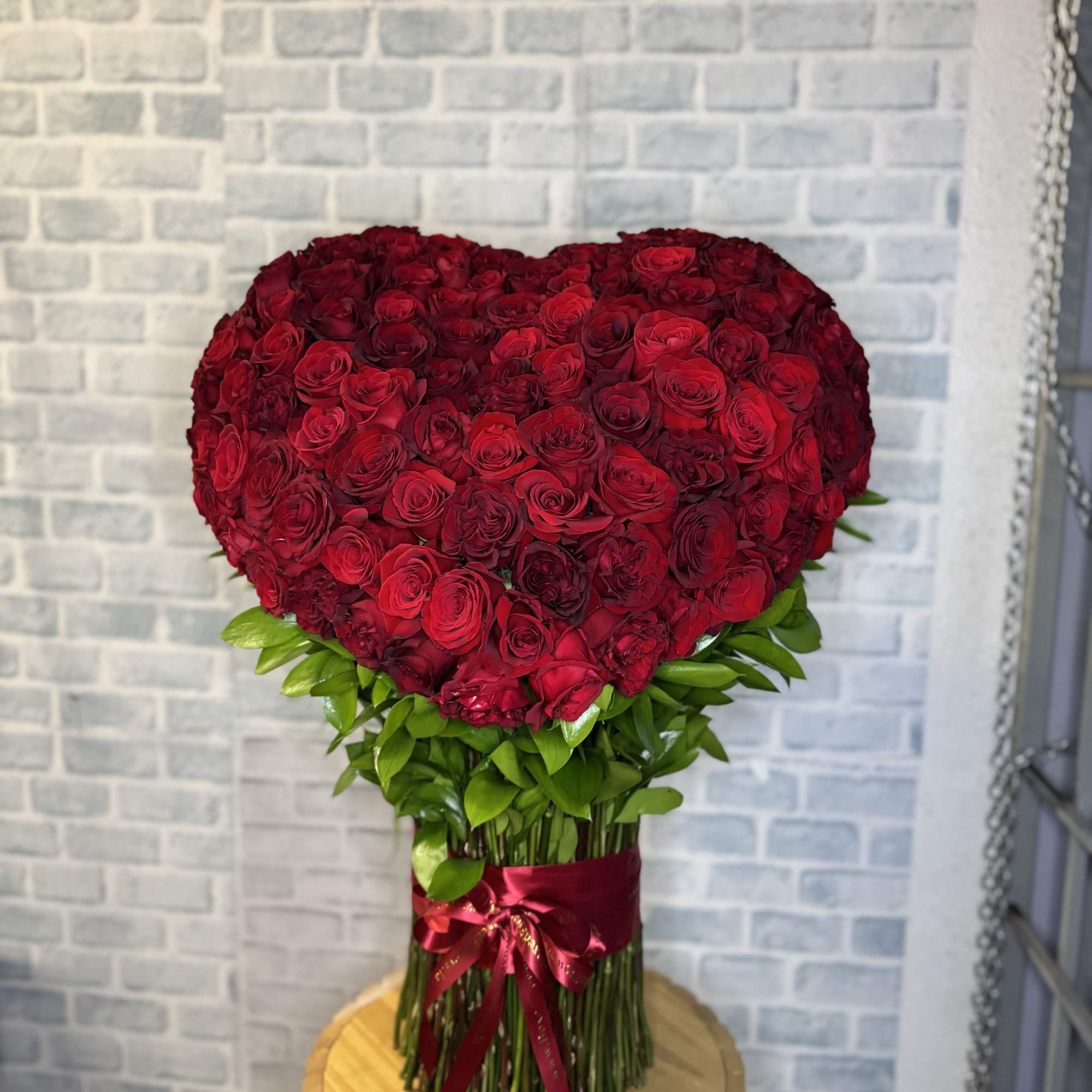 Heart-shaped bouquet of red roses with a ribbon wrap