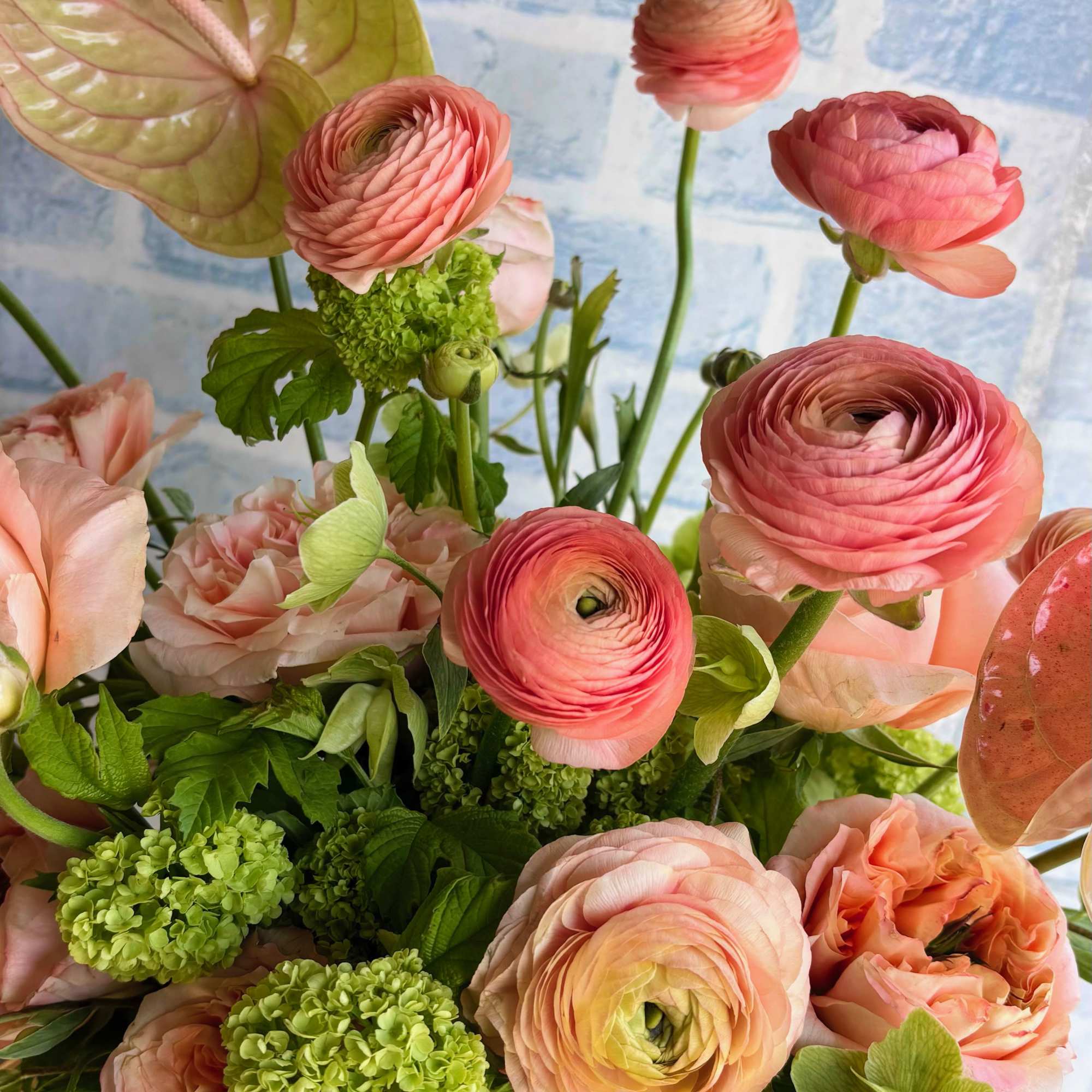 Pink ranunculus and peach roses in a vase with green blooms