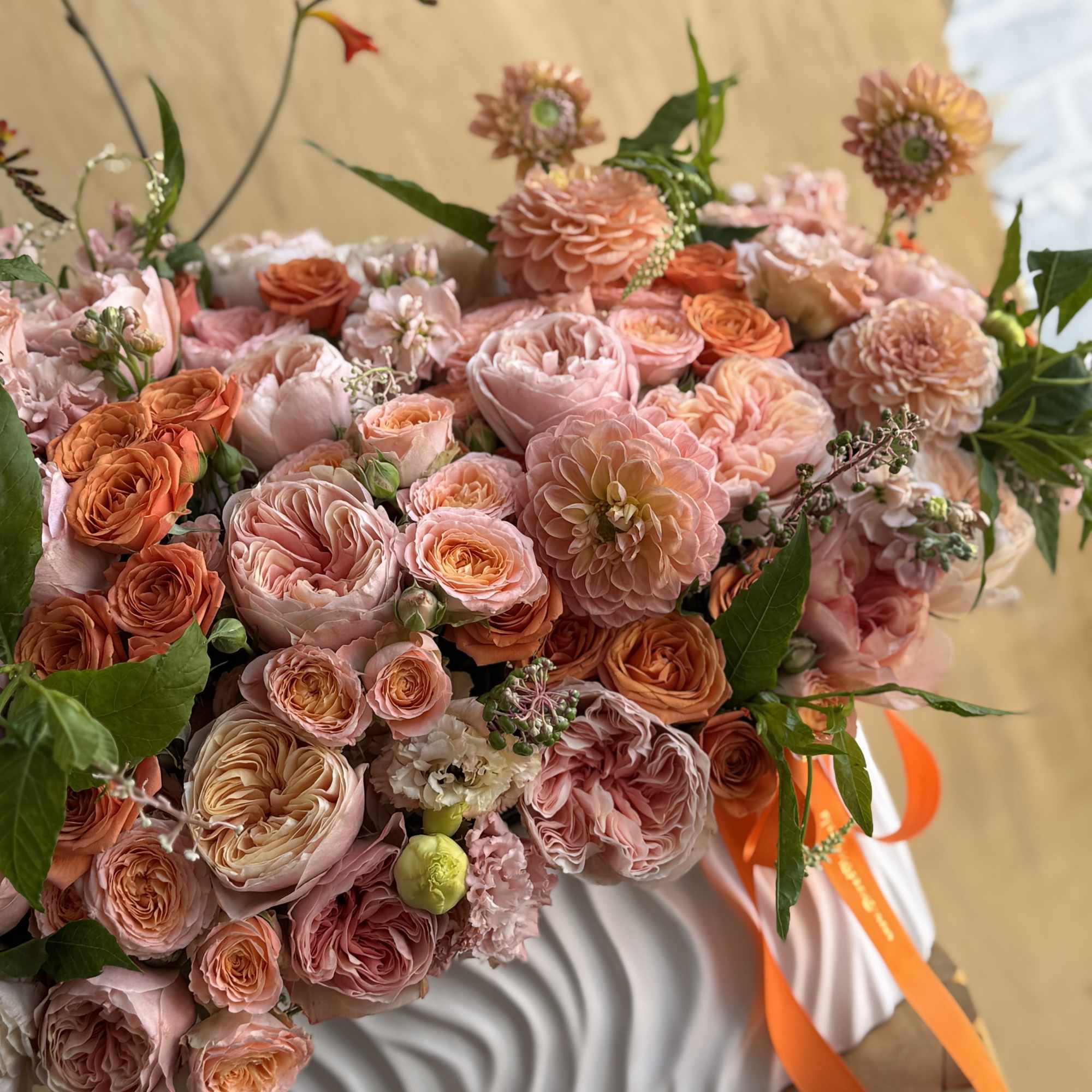 Large bouquet of pink and peach roses with orange ribbon