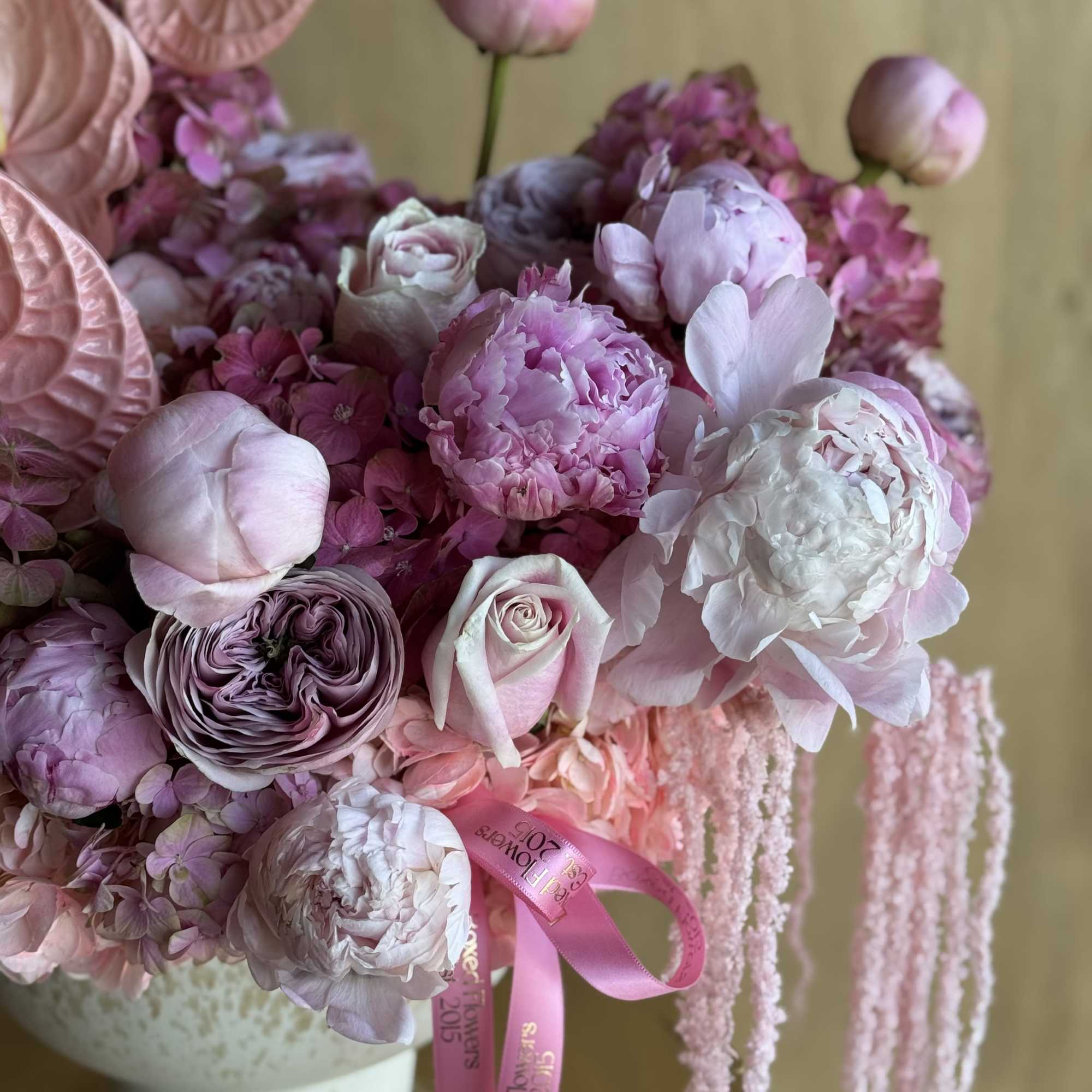 A breathtaking arrangement of soft pink anthuriums, garden roses, peonies, hydrangeas, and