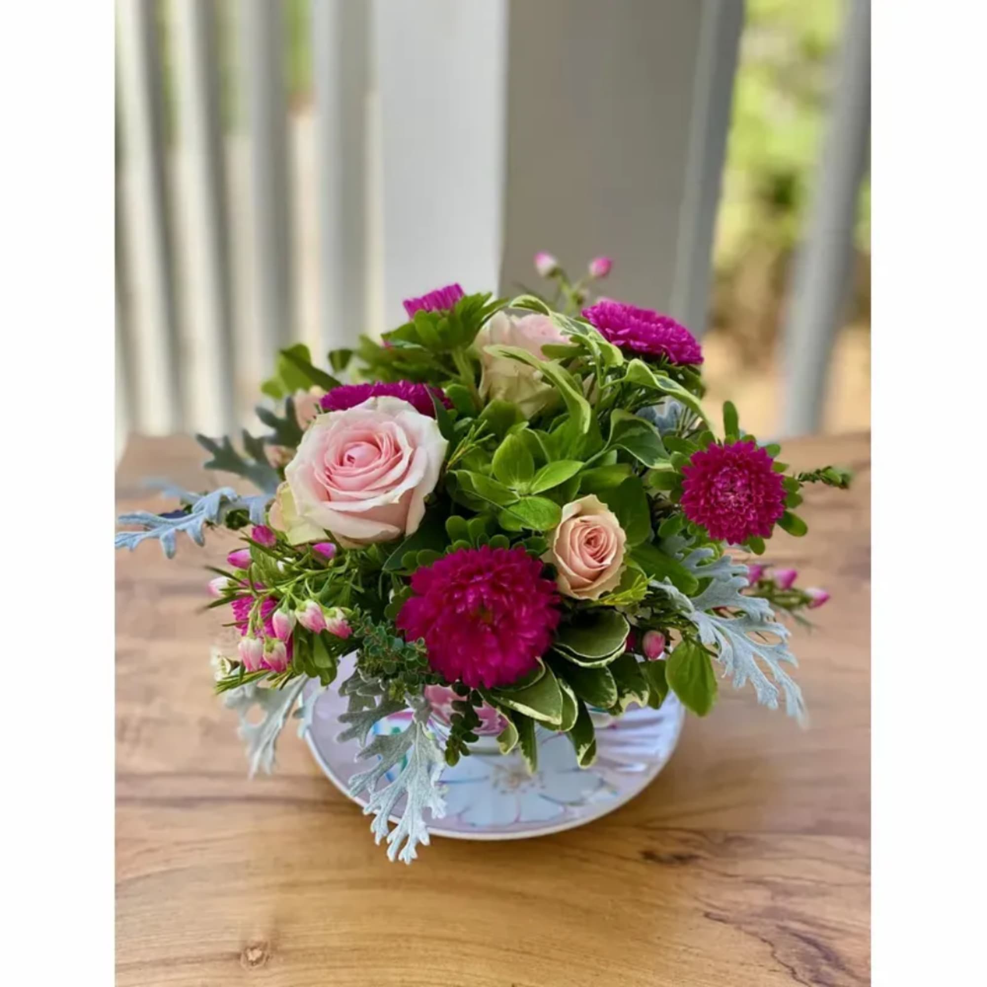 Pink roses and magenta blooms arranged in a white bowl vase