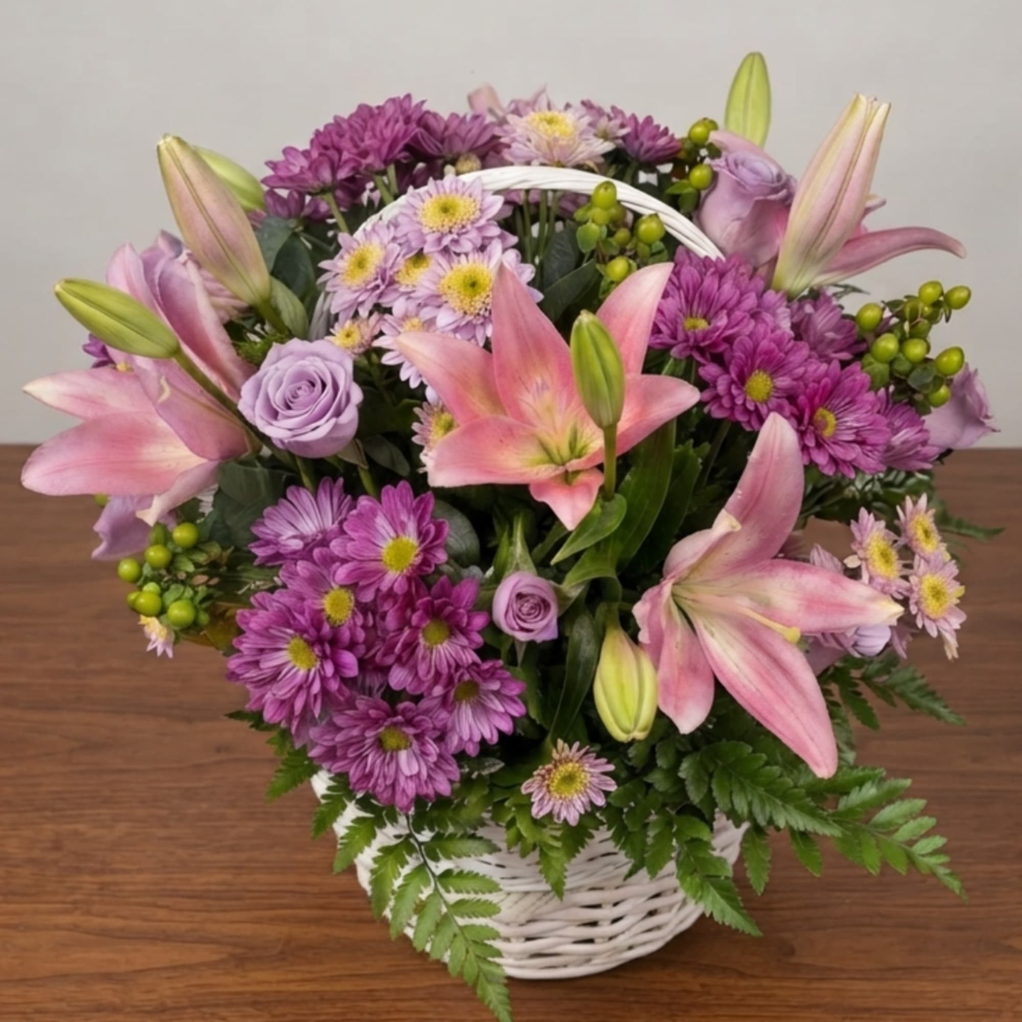 Pink lilies and purple flowers arranged in a white basket, photo 2 of 3