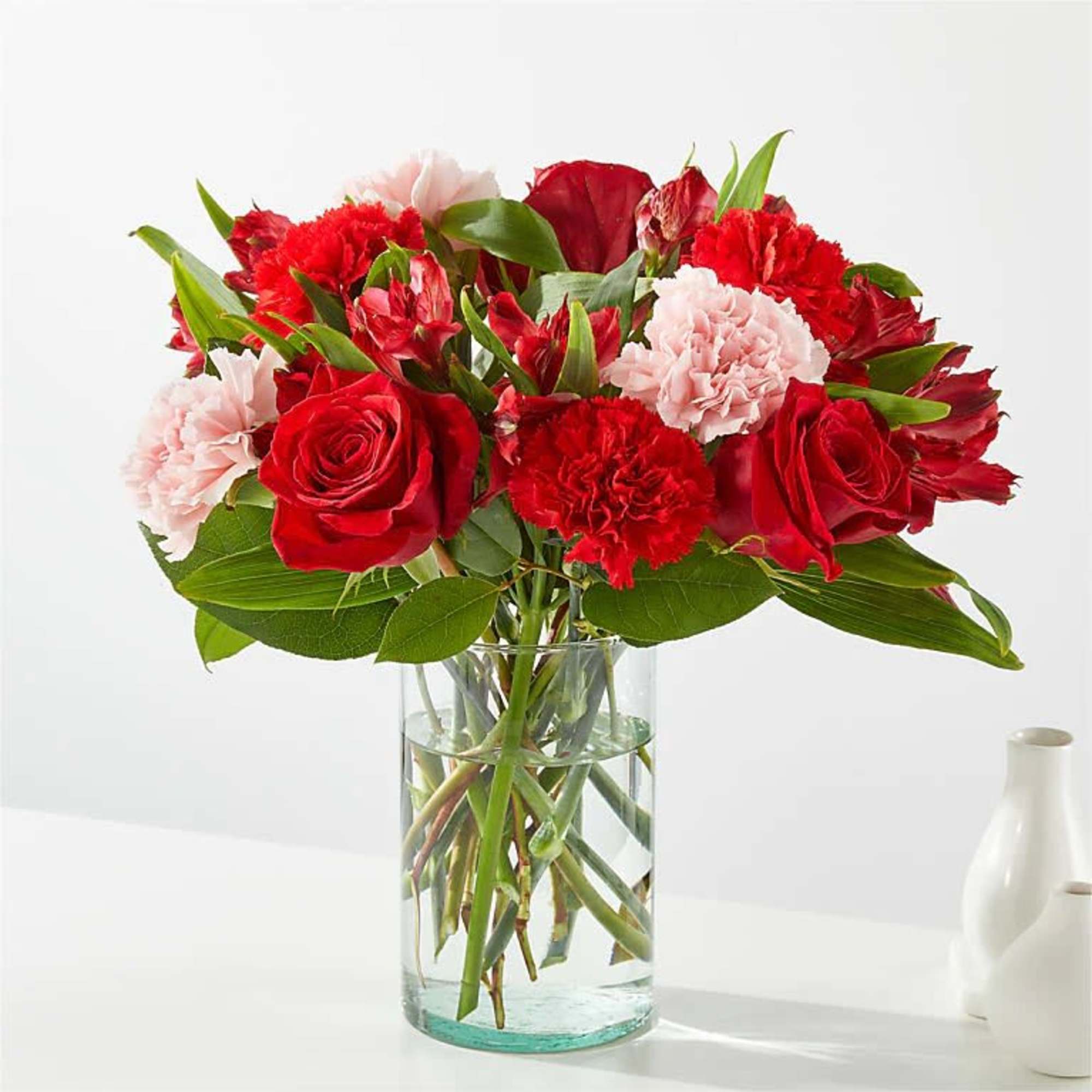 Bouquet of red roses and pink carnations in a clear glass vase