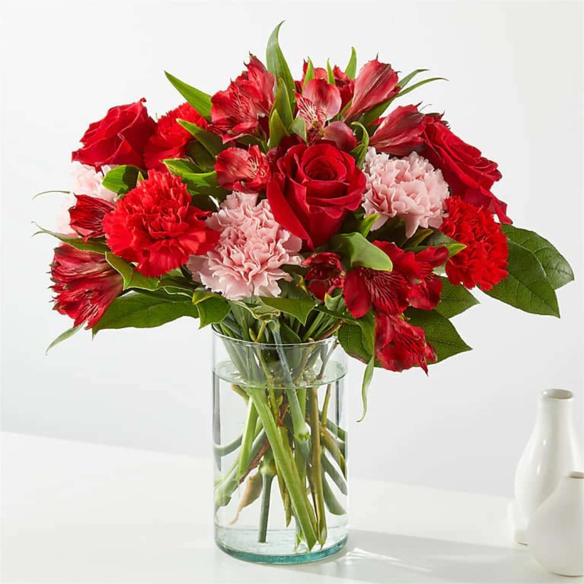 Red roses and carnations in a clear glass vase