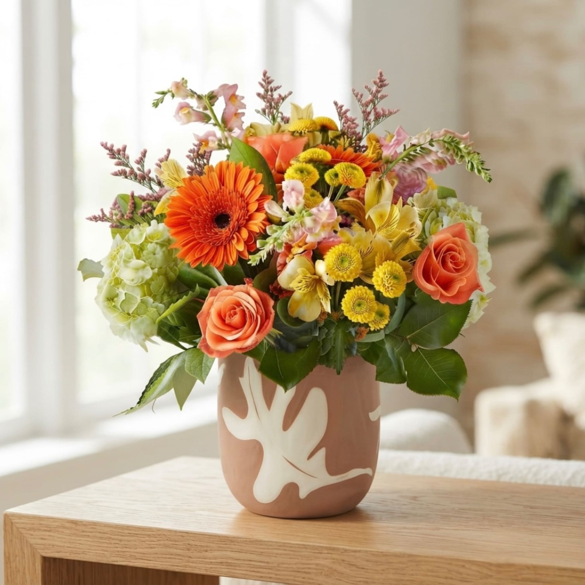 Mixed bouquet in a pink vase with orange, yellow, and pink flowers